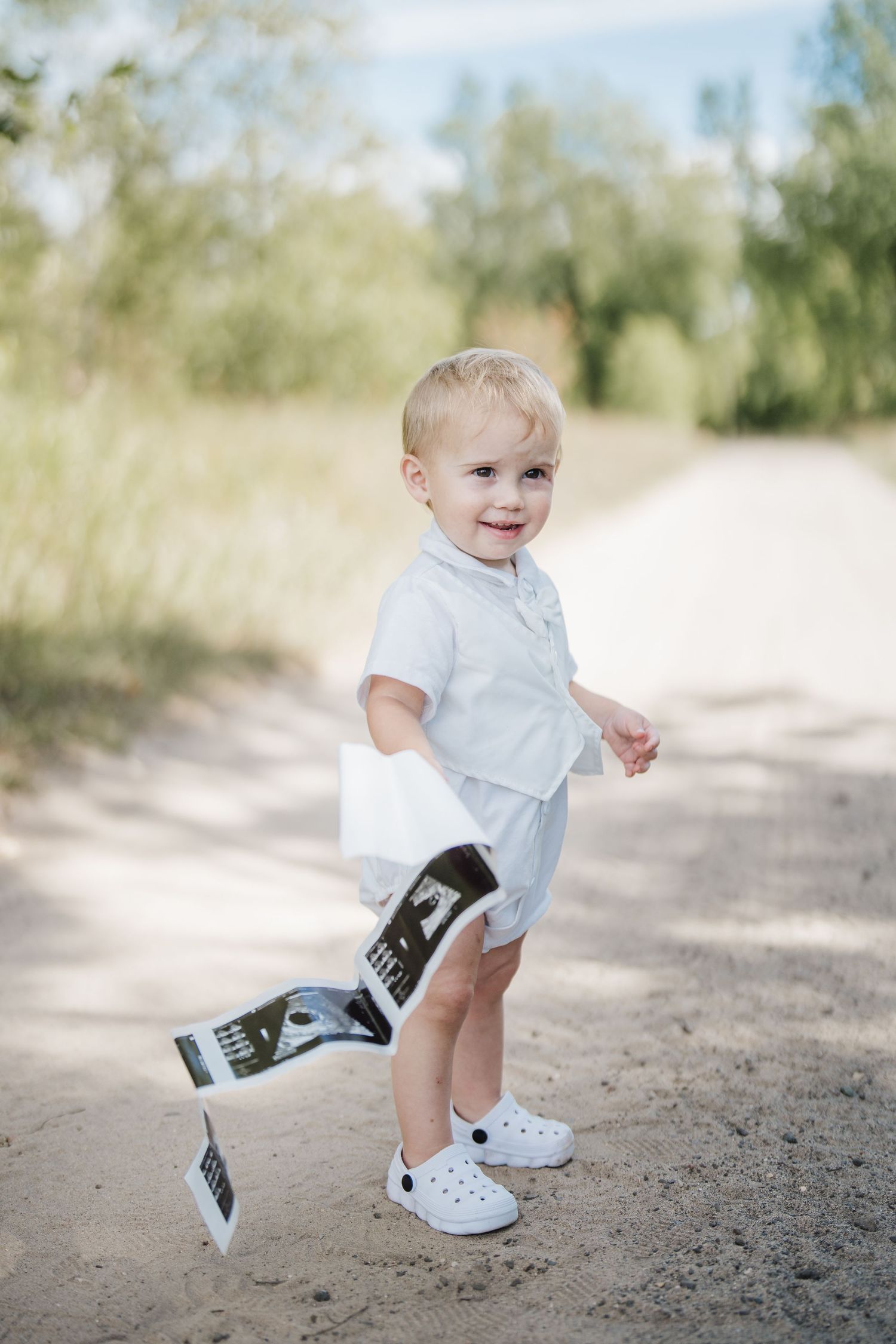 A sequence of photos showing a toddler in white clothing taking steps on a dirt path.