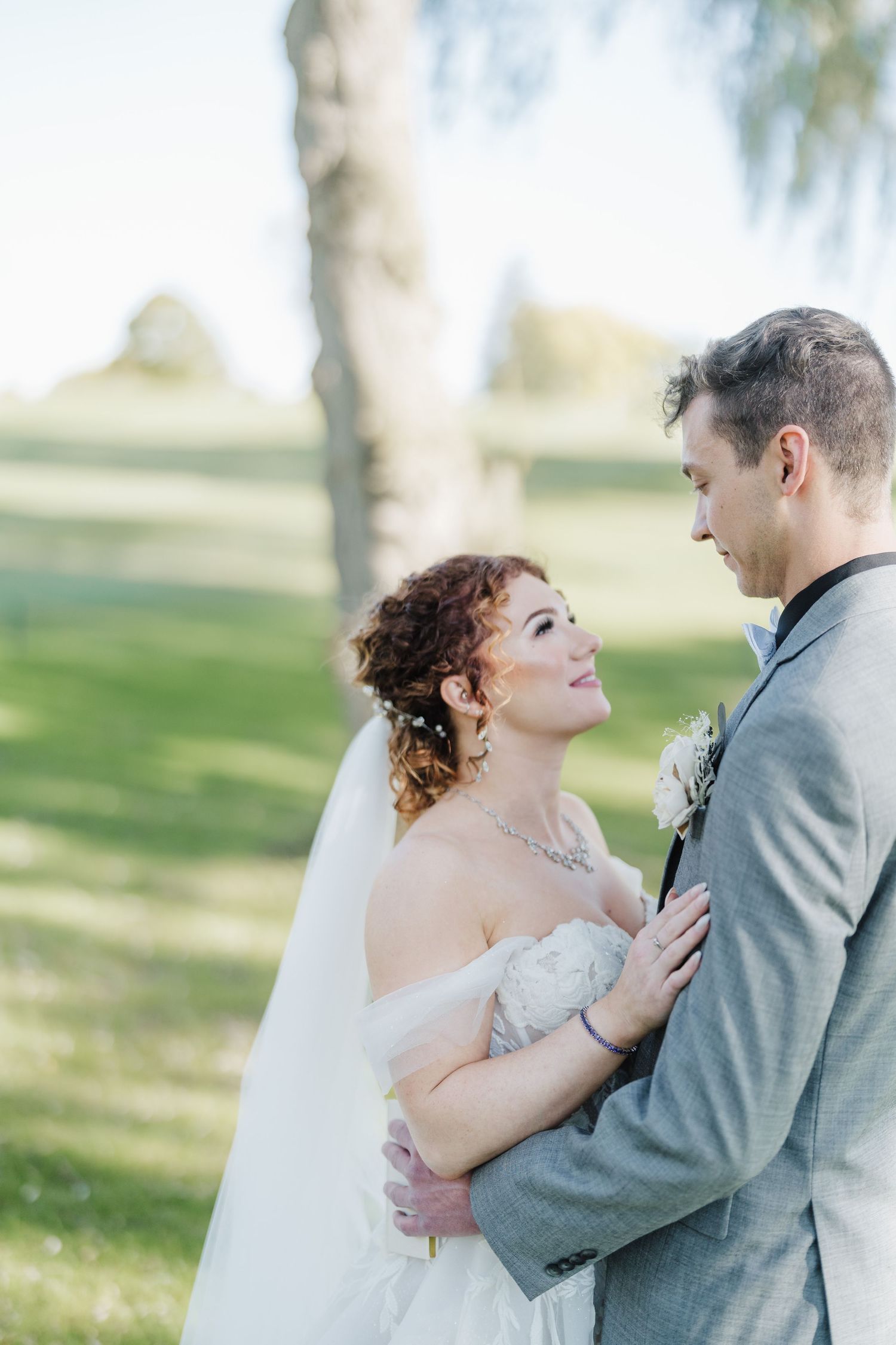 Romantic moment between couple in wedding attire against a soft focus natural backdrop.