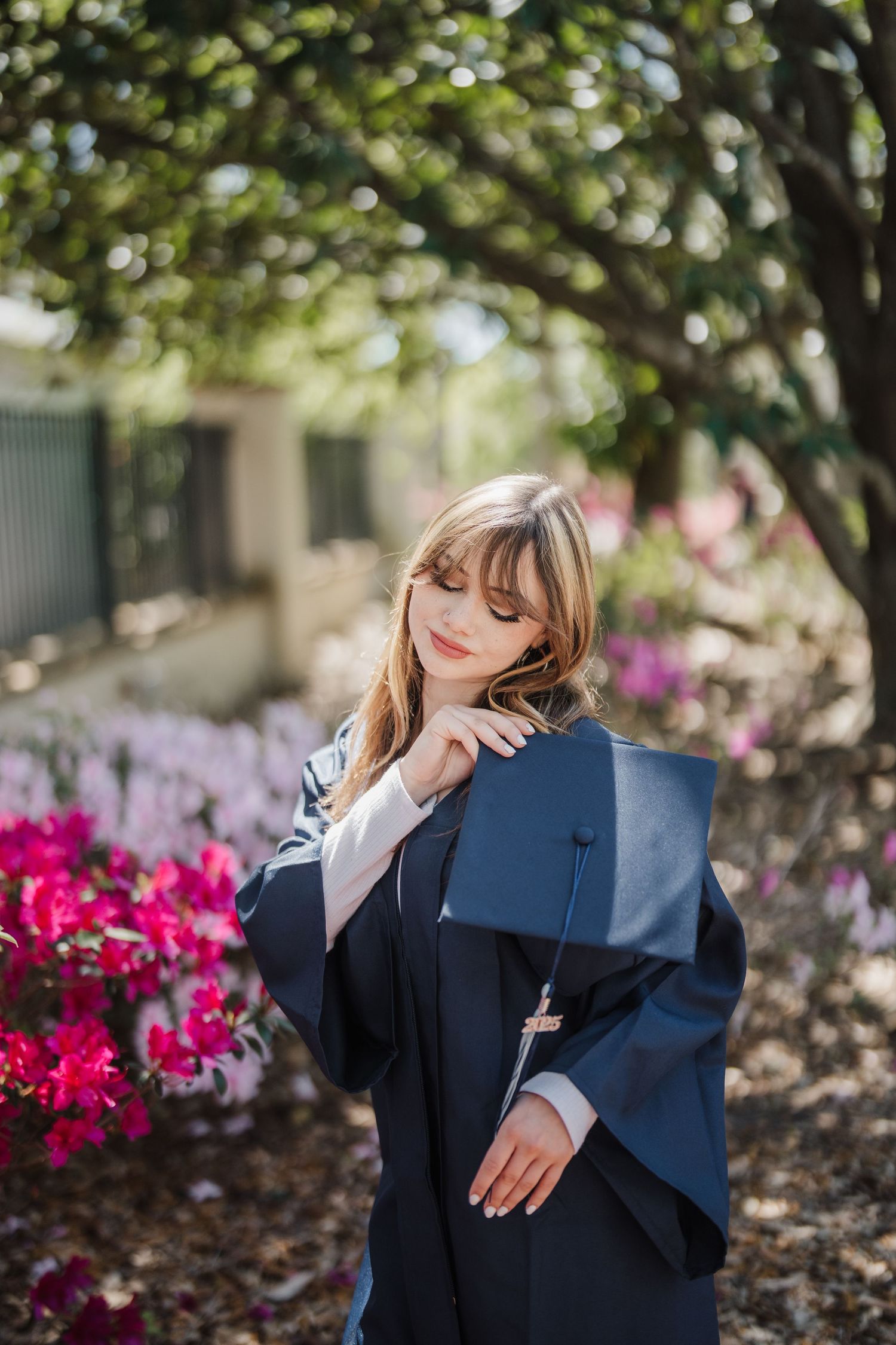 Figure in dark academic attire posed against vibrant pink flowers and garden foliage.