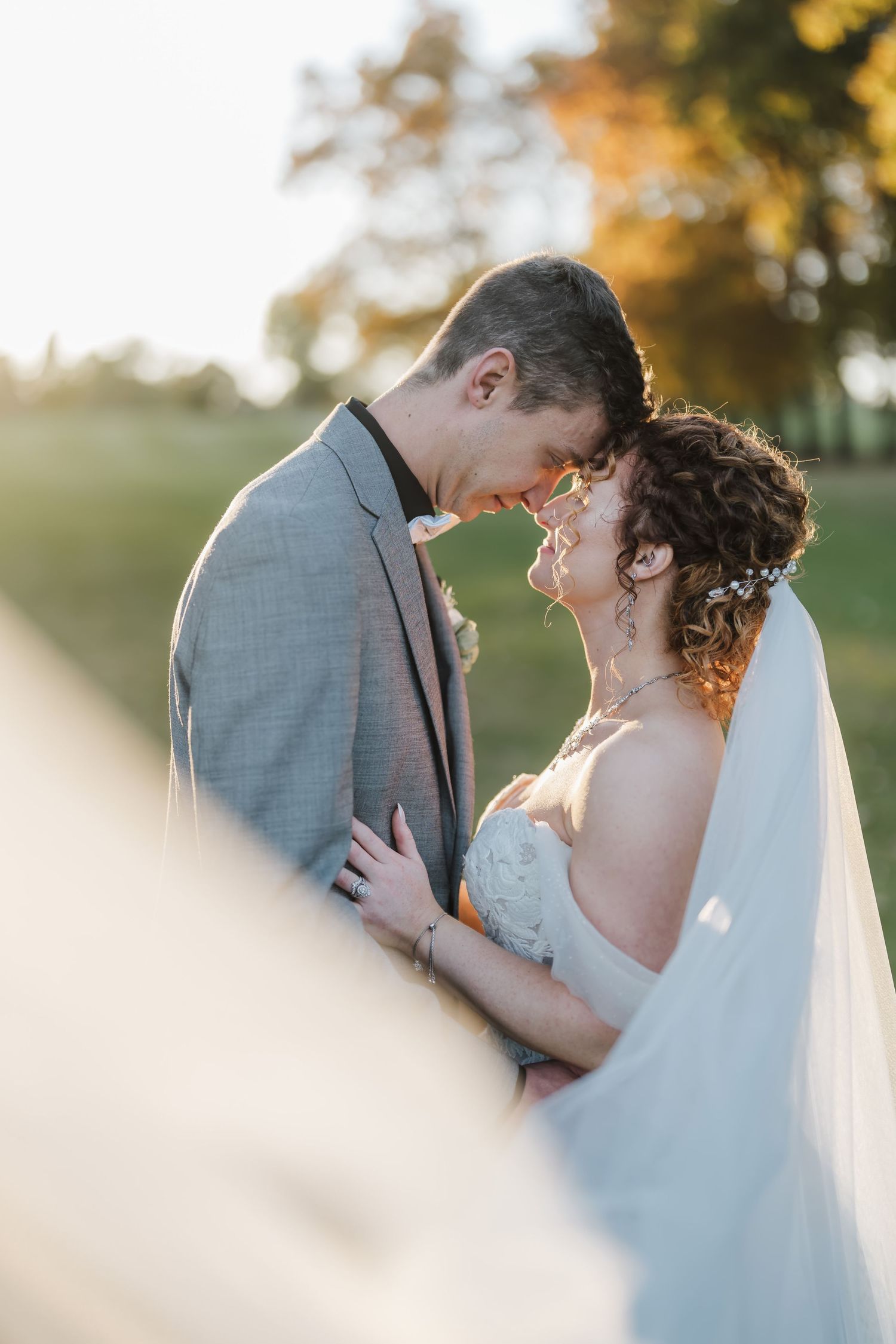 A tender moment between newlyweds at sunset as they share an intimate embrace outdoors.