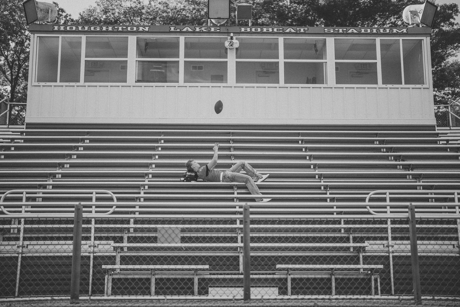 Metal bleachers with green seats stand empty against a white and glass stadium structure.