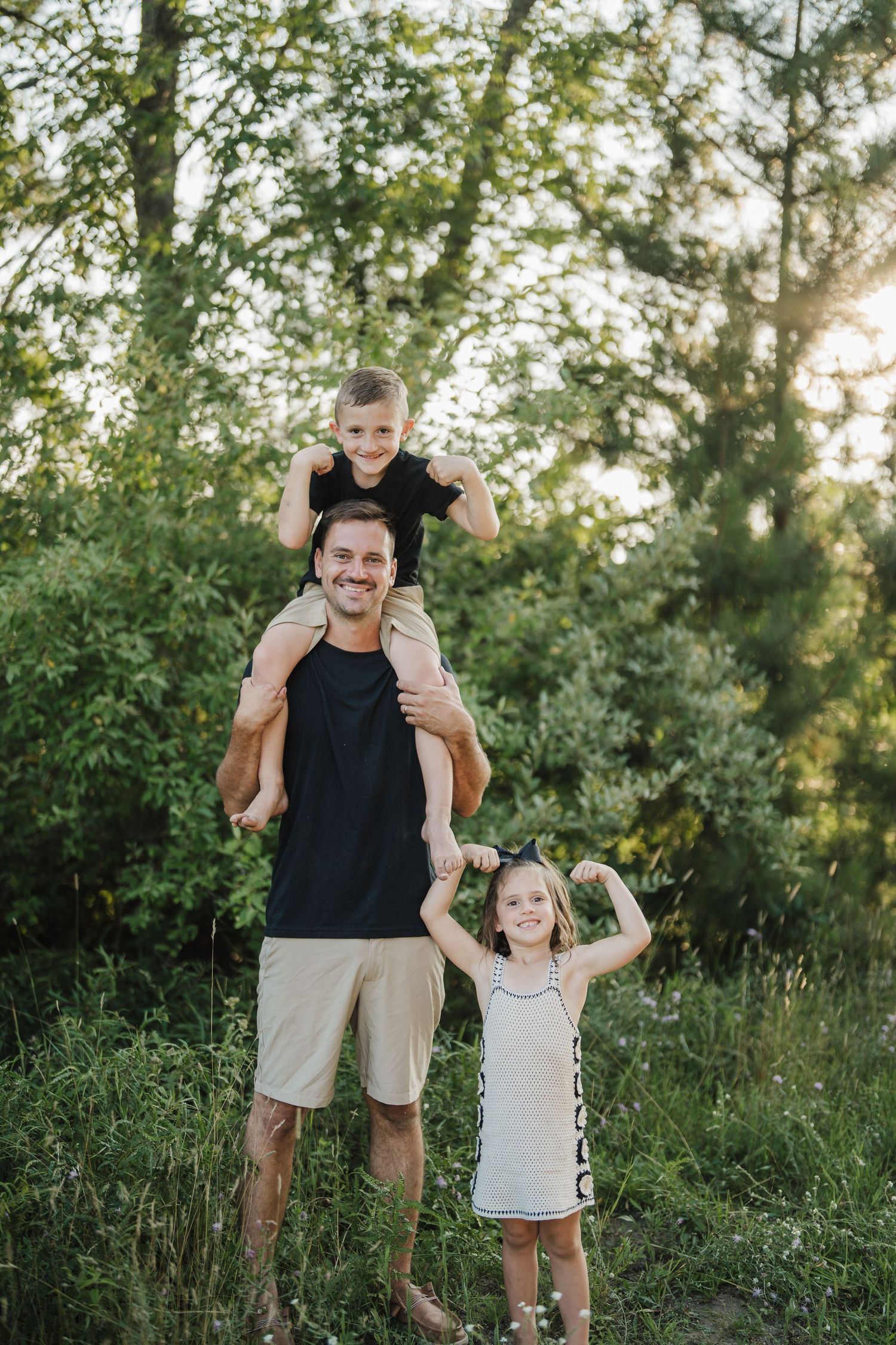 A playful family portrait session outdoors with everyone laughing and having fun among trees at sunset.