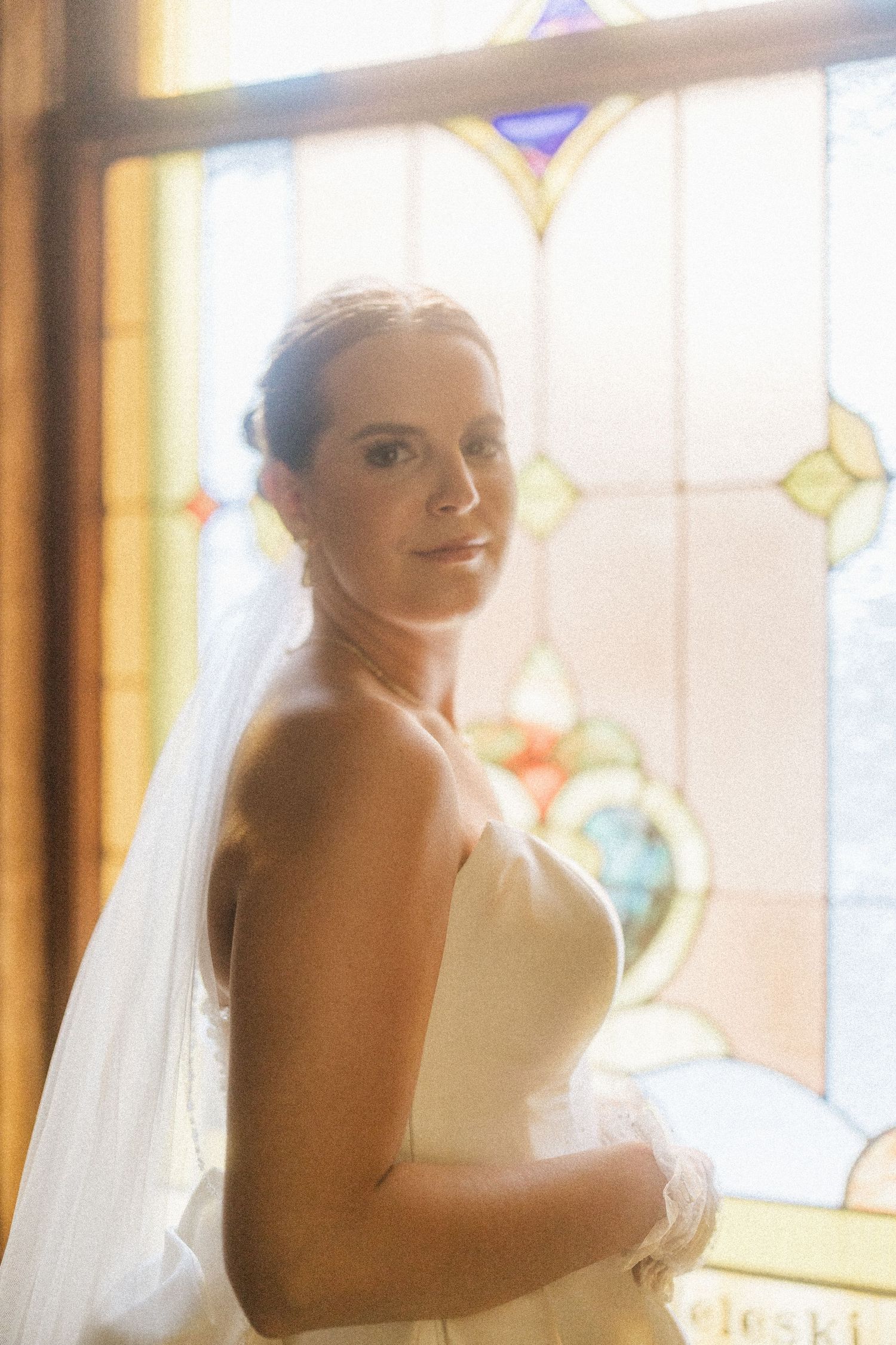 Ethereal bridal portraits with stained glass windows casting soft light on a flowing white wedding gown.