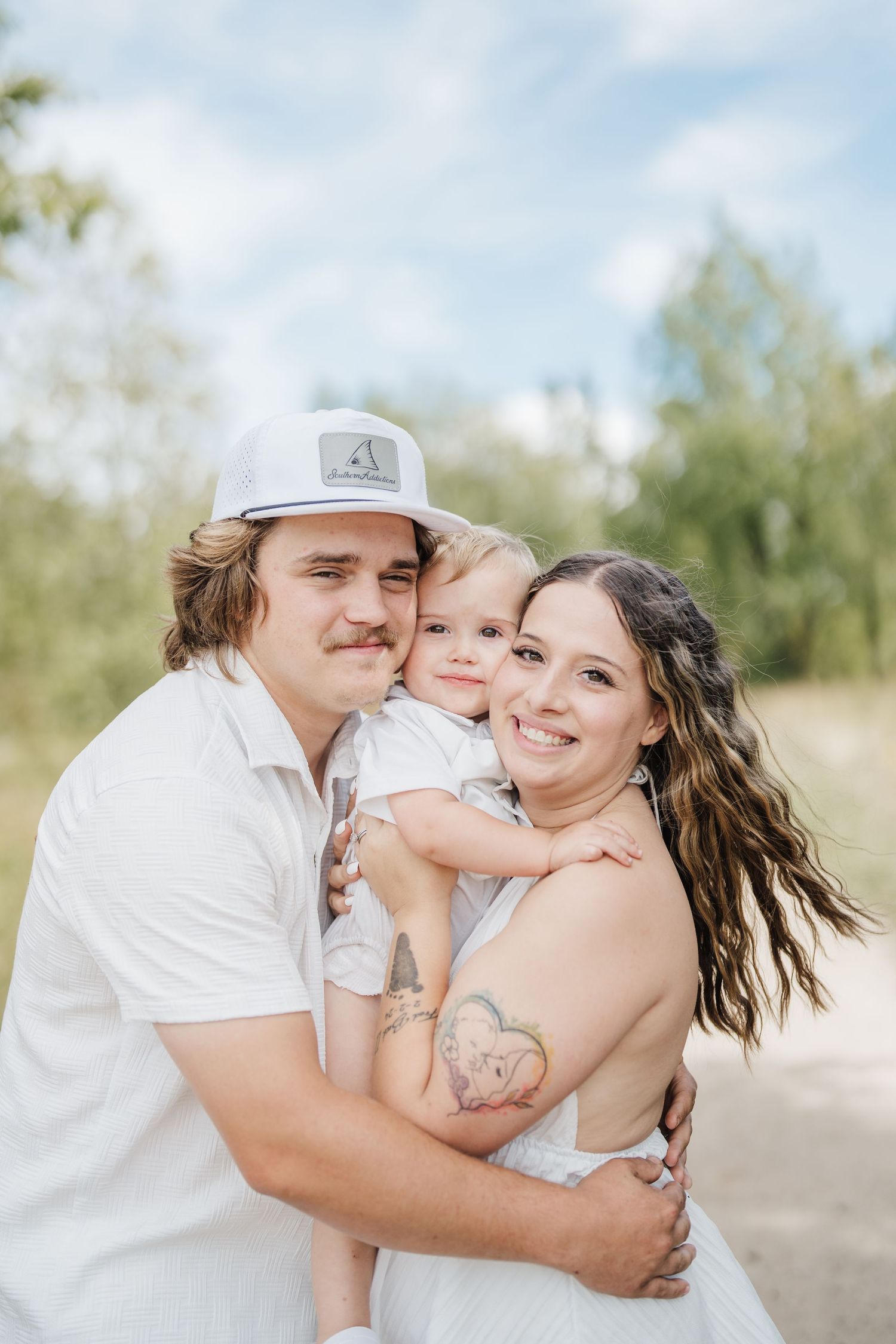 A family wearing white outfits shares joyful moments together outdoors on a sunny day.