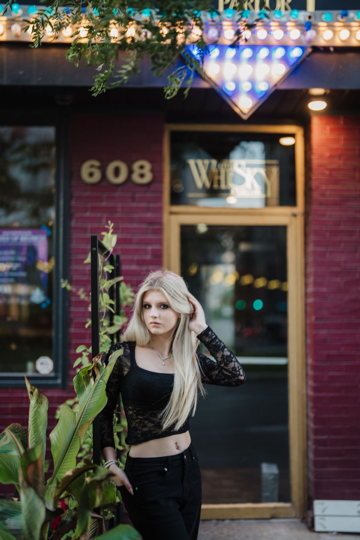 Moody urban photoshoot with string lights and brick buildings creating an atmospheric evening ambiance.