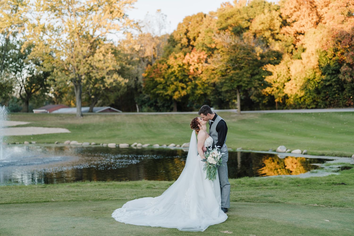 Newlyweds embrace by pond during golden hour wedding photos.