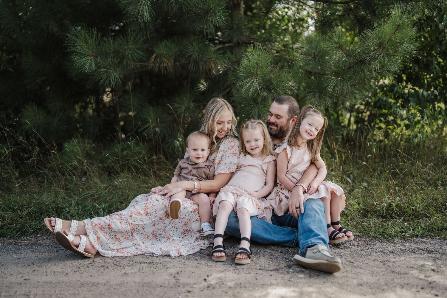 A group of people lying on a dirt path in coordinated outfits for a casual outdoor photo session.