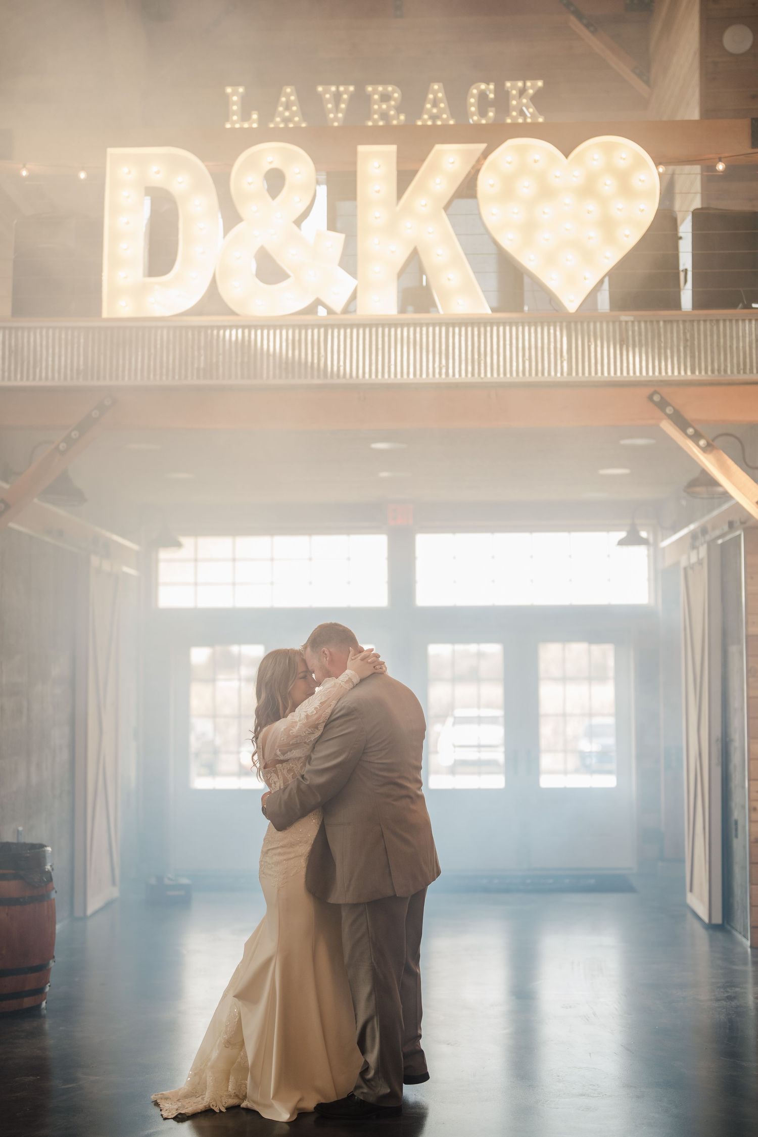 A couple shares their first dance under illuminated D&K marquee letters at Layback.