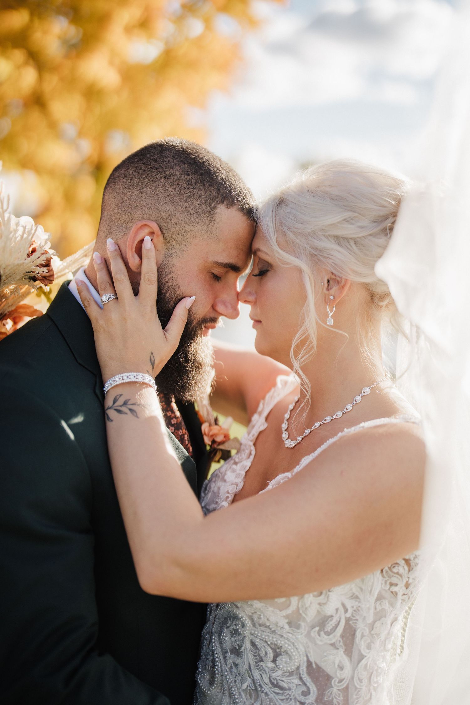 Romantic wedding couple embraces in an intimate moment against a golden autumn backdrop.