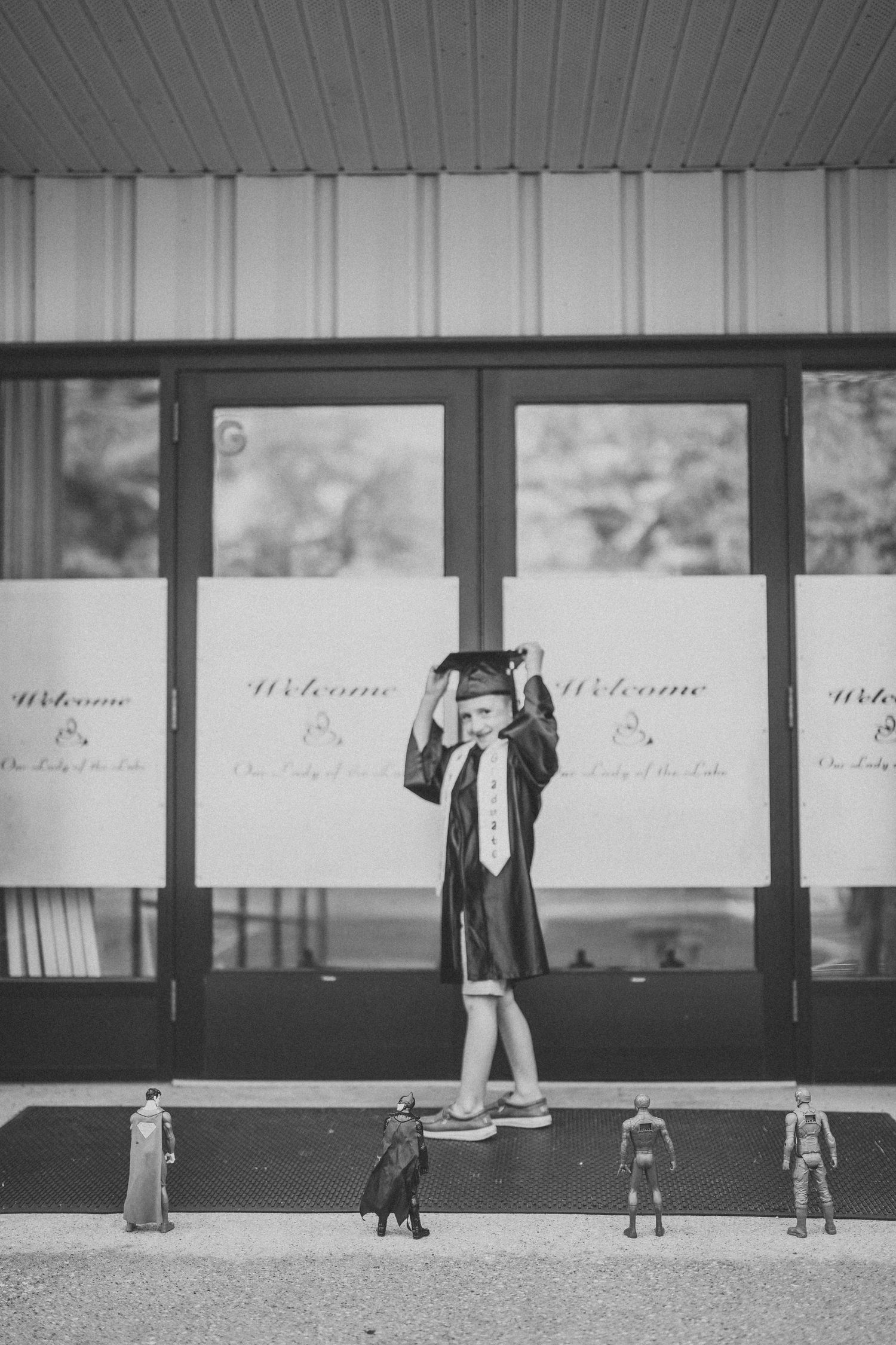 Black and white image of children walking past a storefront with welcome signs in the windows.
