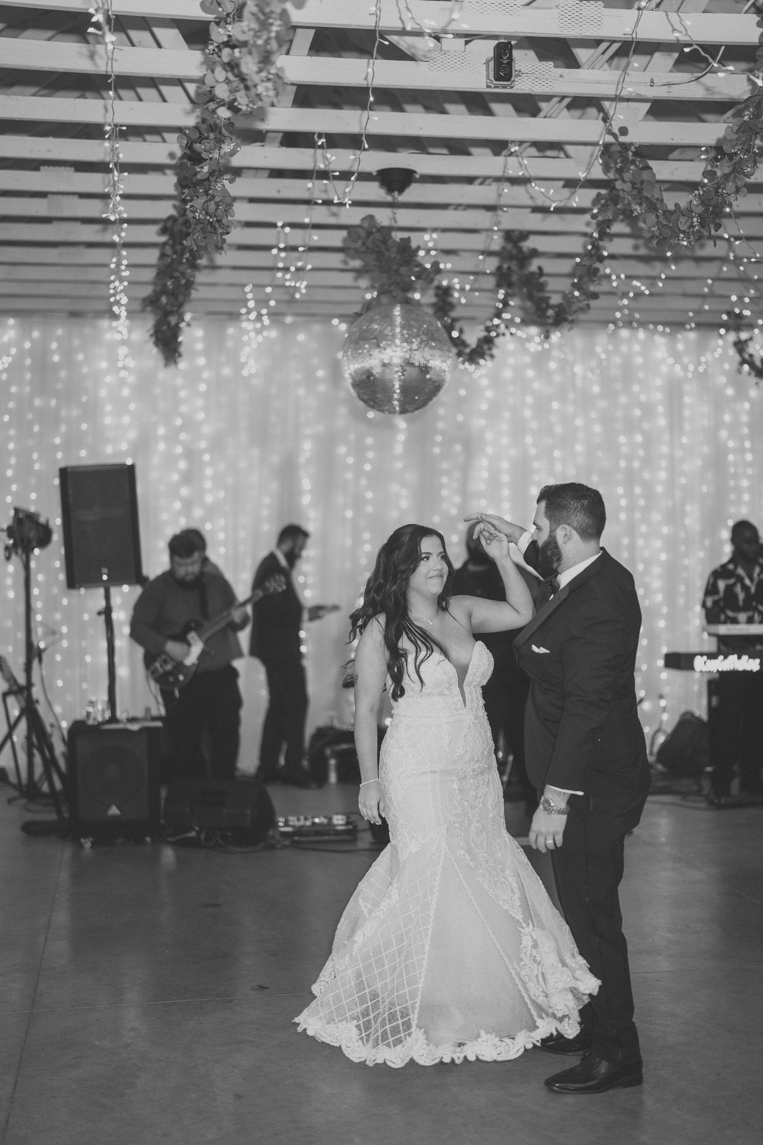 Wedding reception dance floor with string lights and couples dancing in black and white.