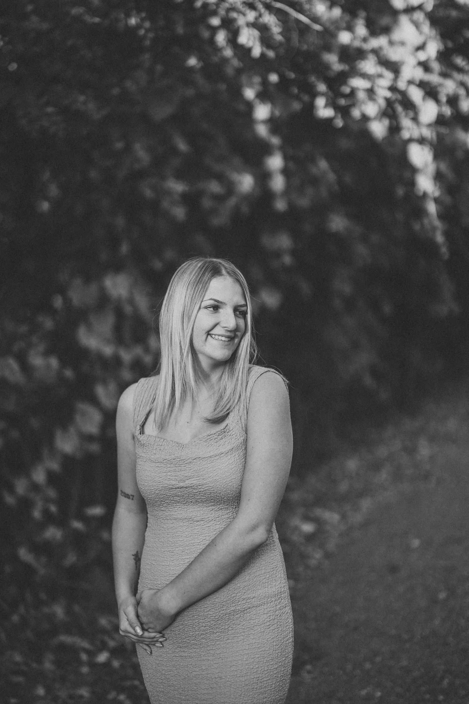 Black and white portrait series showing candid expressions and natural poses against a wooded backdrop.