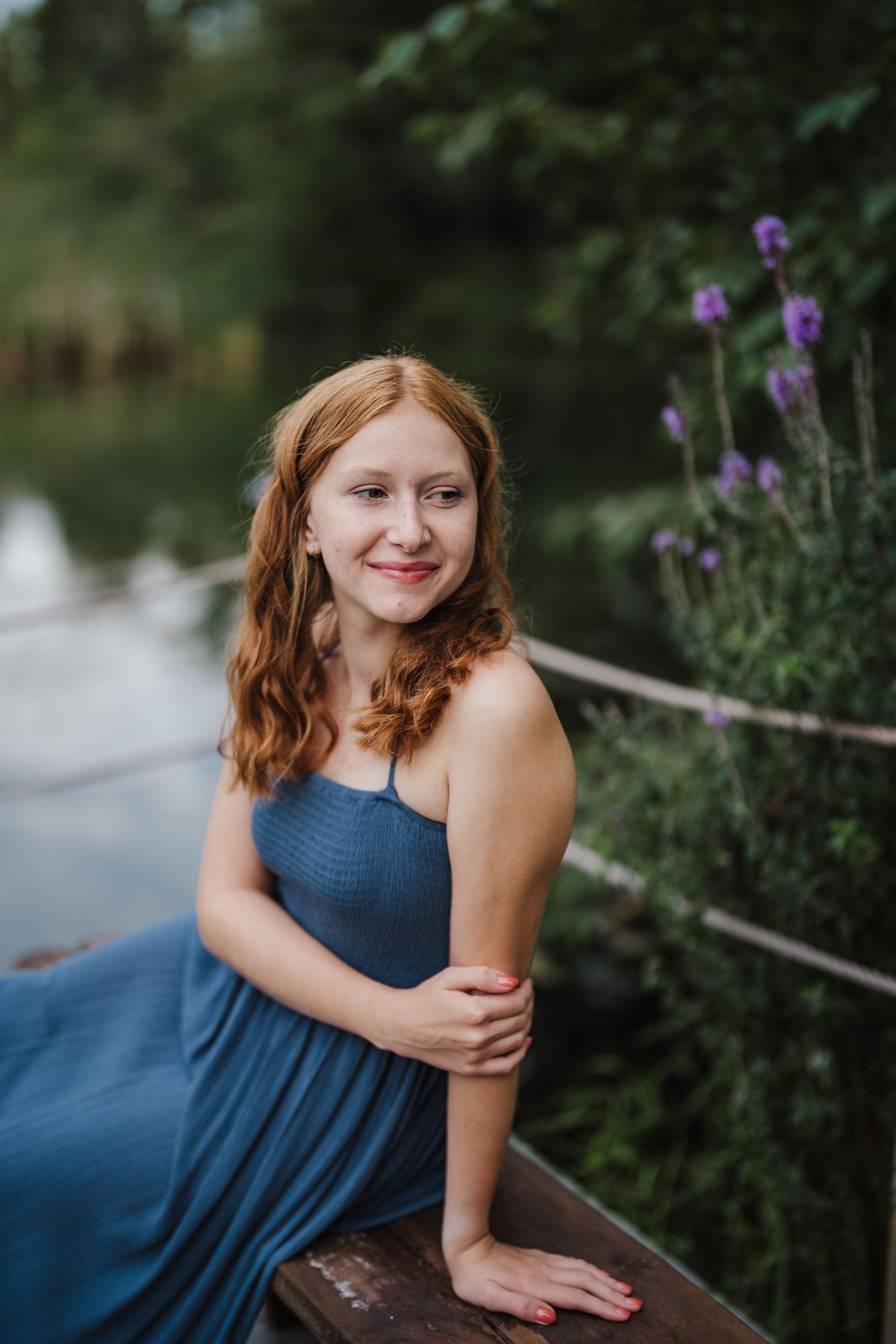 A flowing navy blue dress is captured in an artistic outdoor portrait series with purple wildflowers in the background.