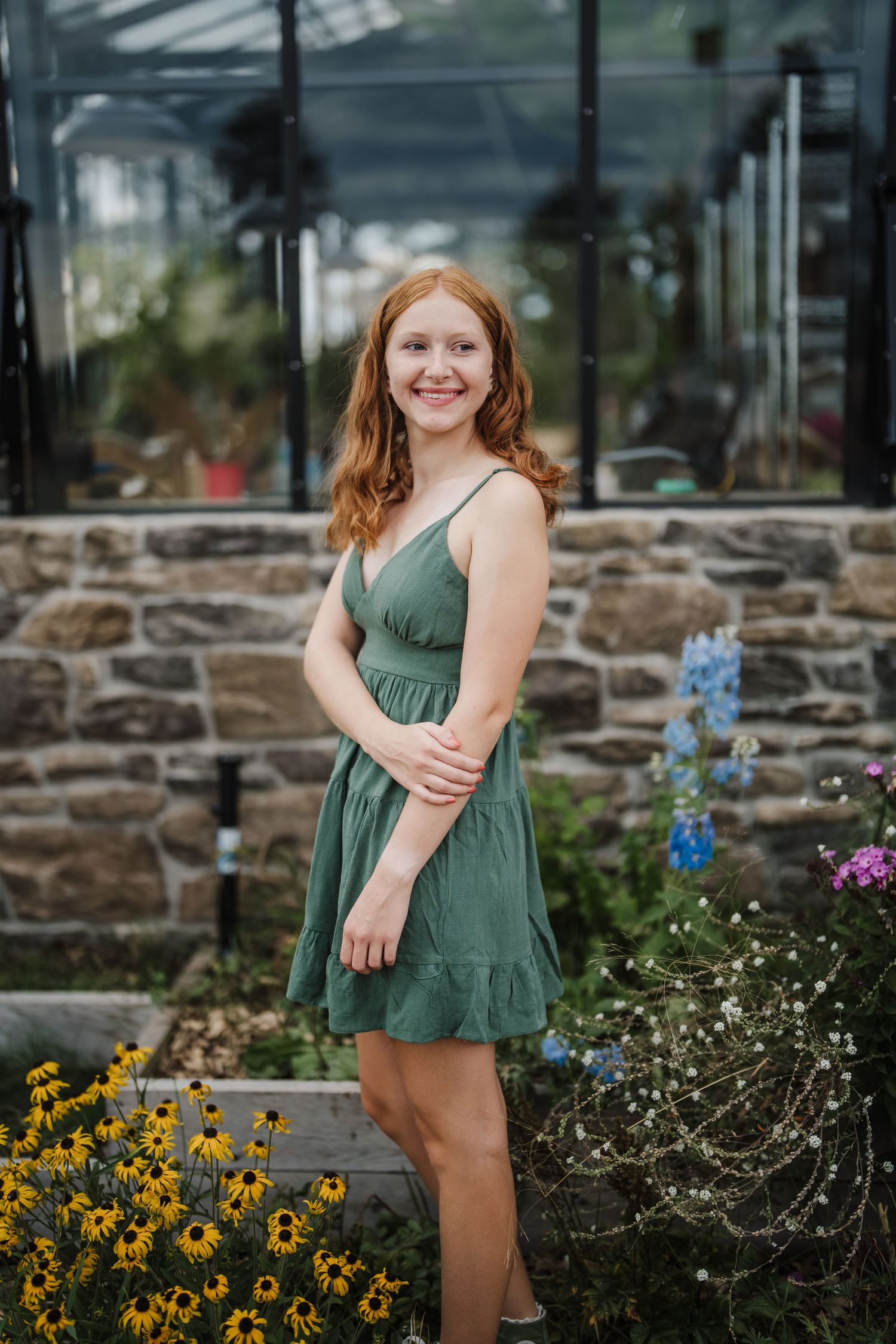 A sequence of poses captured in front of a stone wall with vibrant yellow and purple flowers in a garden setting.