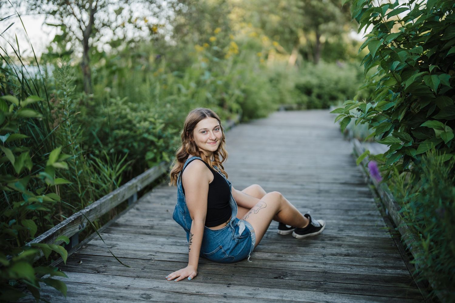 A series of photos showing someone posing on a wooden boardwalk surrounded by lush green foliage.