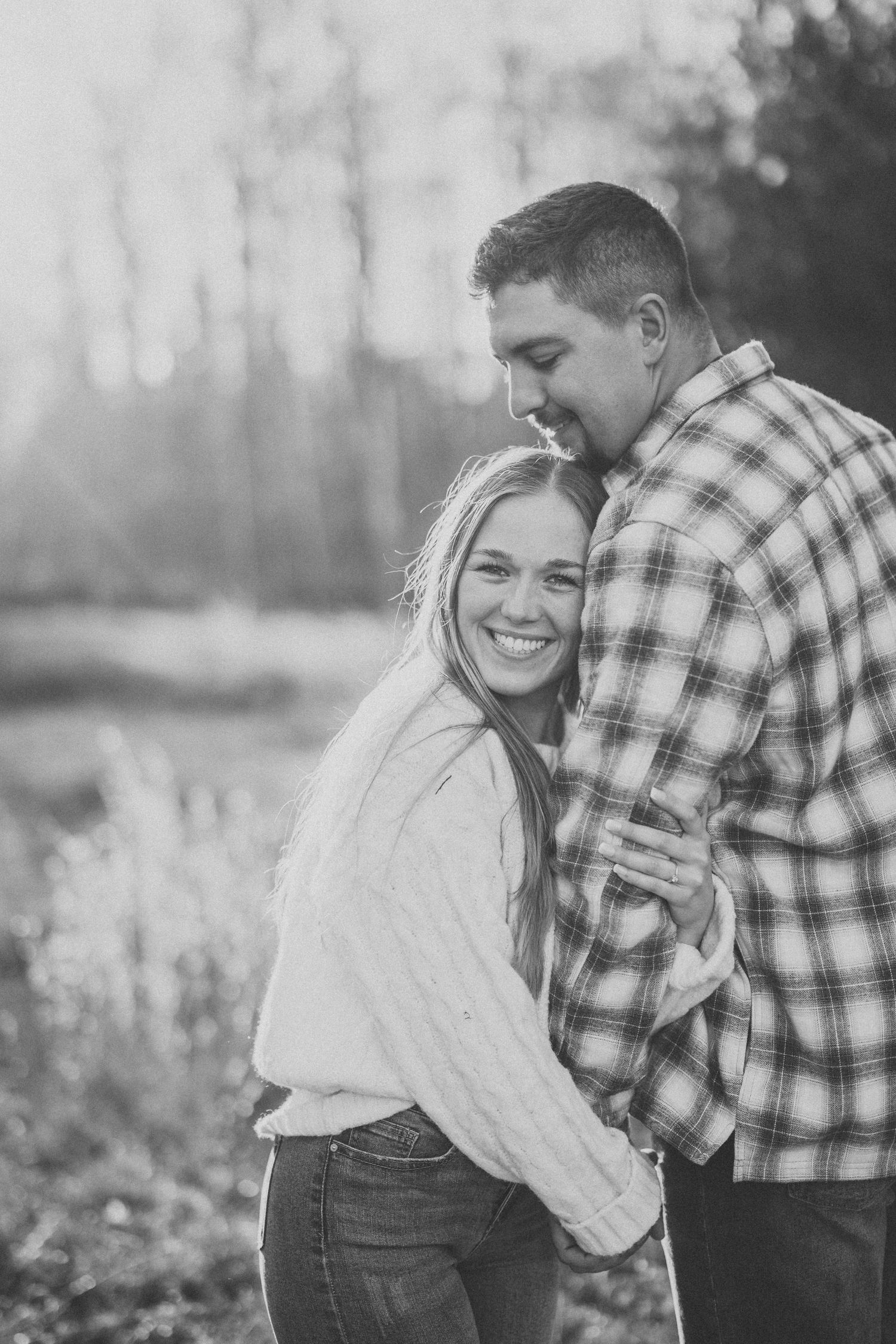 Black and white photo series of a couple embracing and laughing together in a romantic outdoor setting.