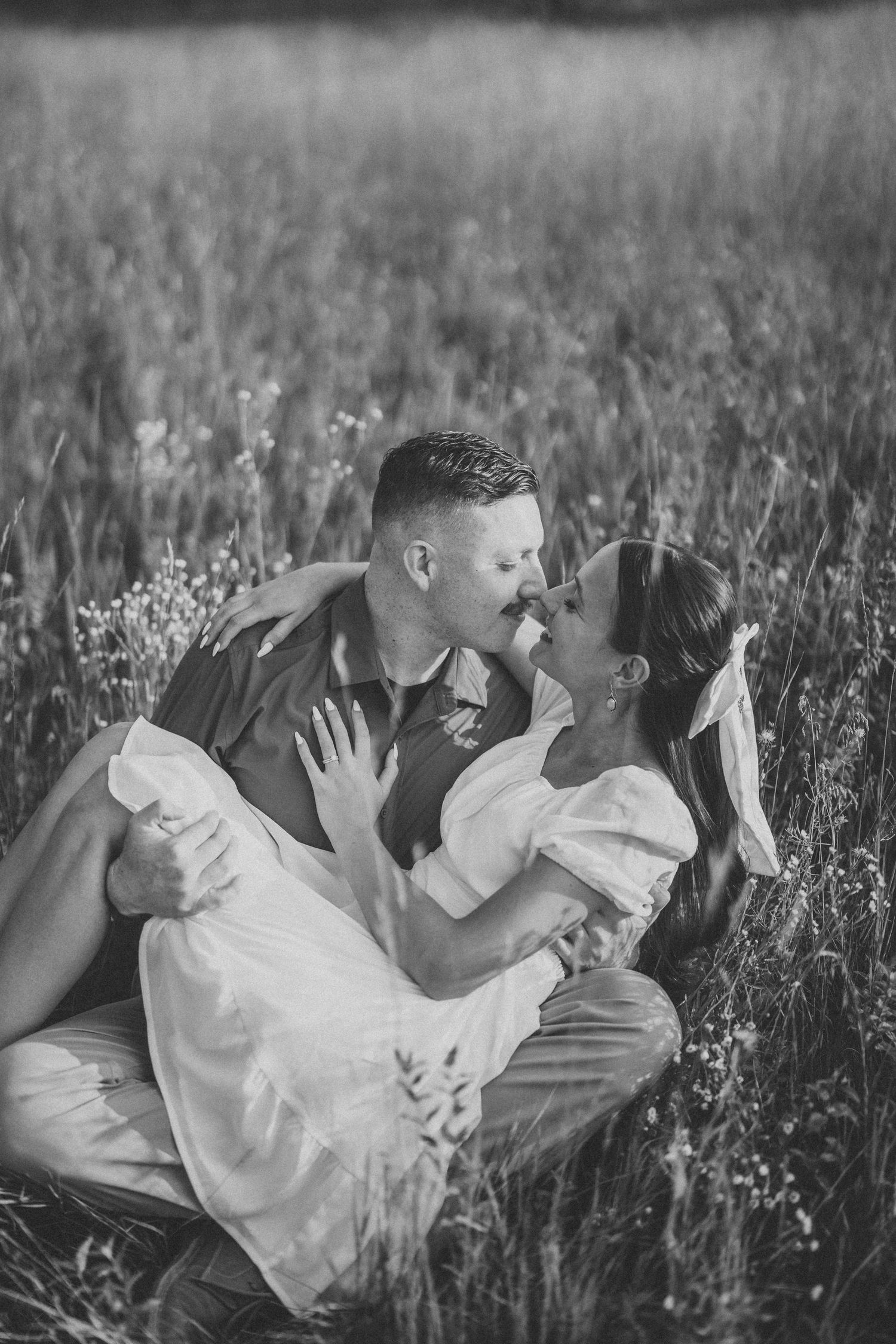 Two people share an intimate moment lying together in a wildflower meadow.