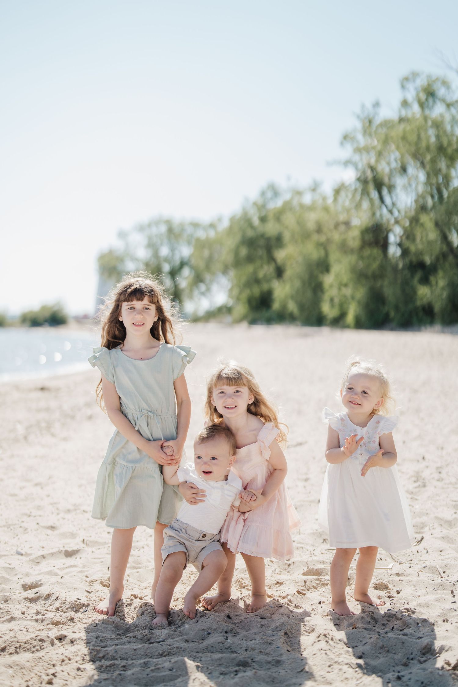 Children playing and laughing together on a bright sandy beach during a summer day.