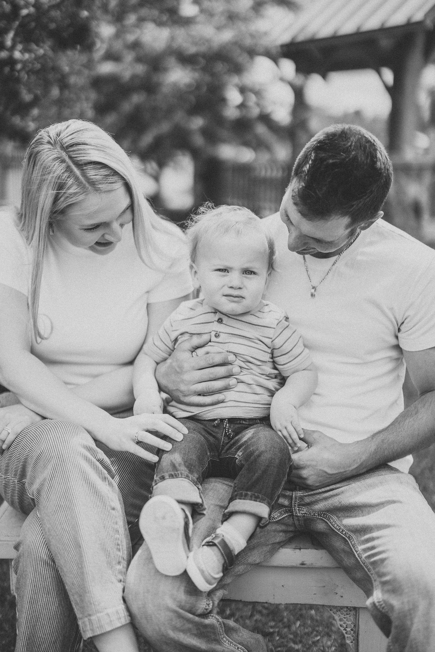Black and white photo series showing tender moments between a parent and baby sitting outdoors.