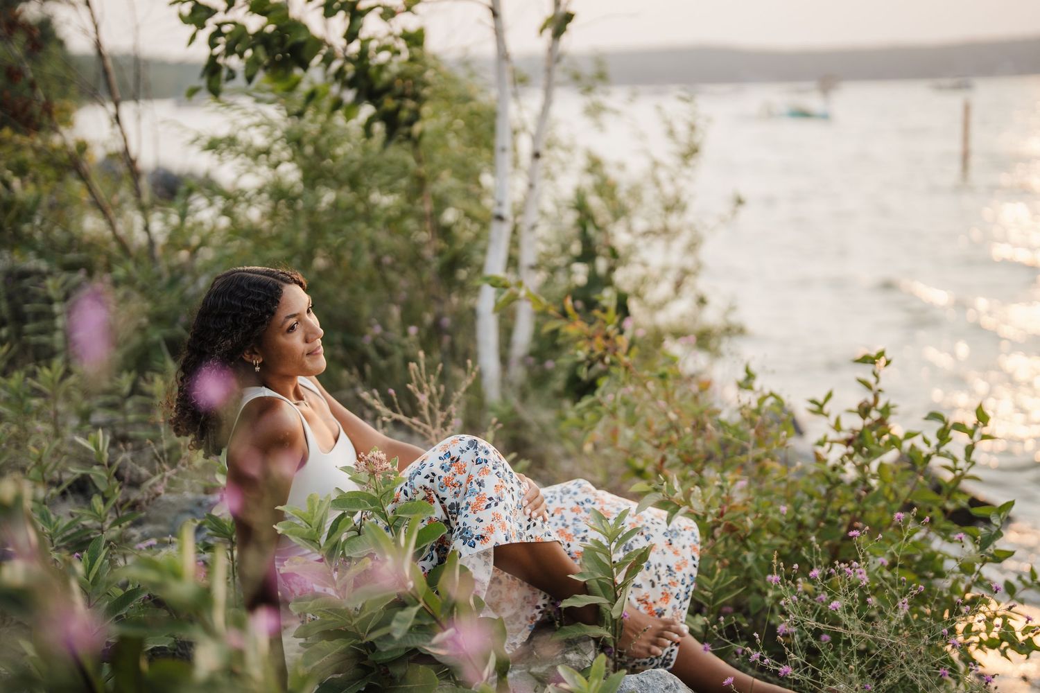 Woman in floral dress twirls joyfully in a sunlit garden during golden hour.