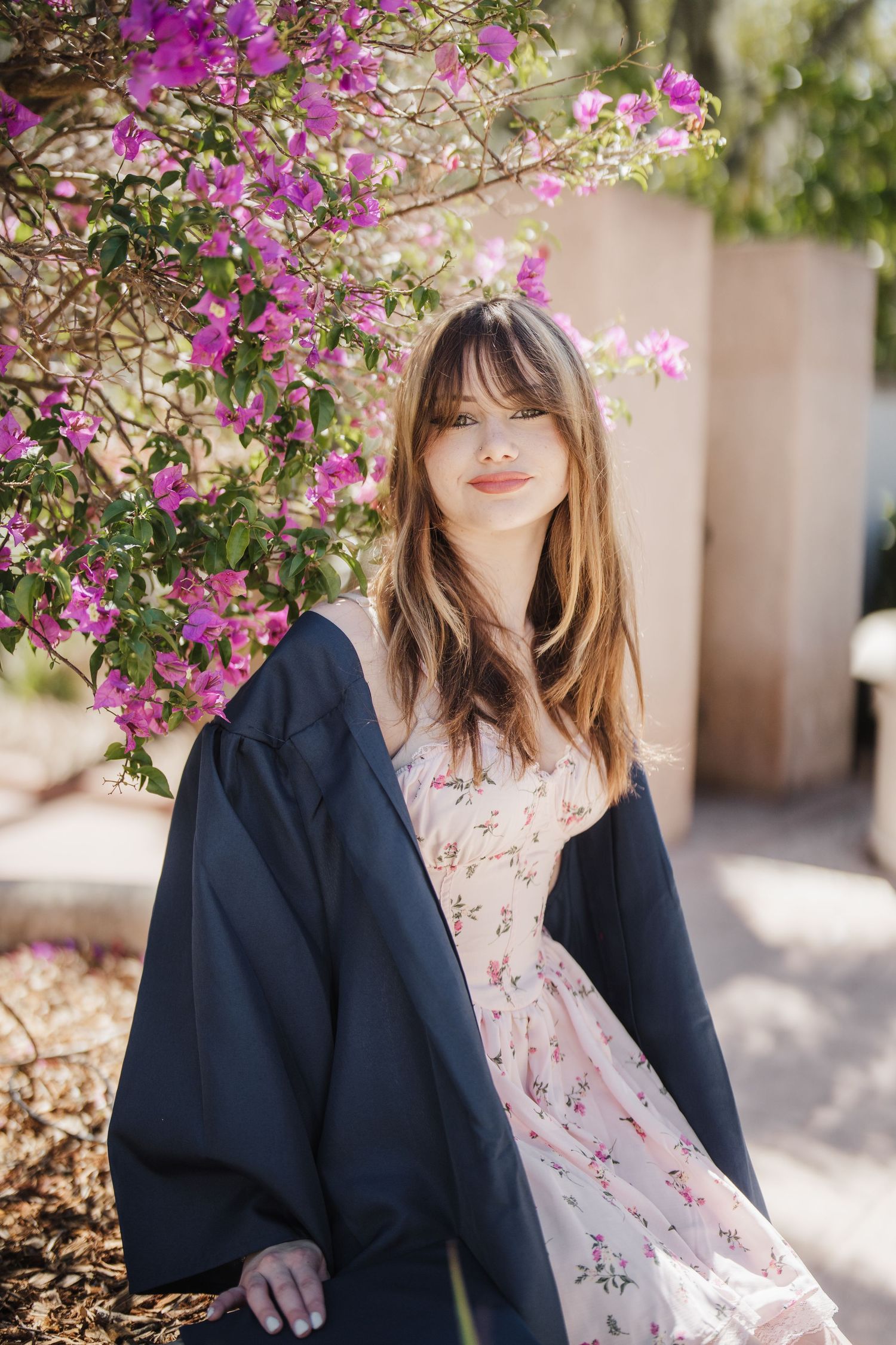 A romantic portrait with vibrant bougainvillea flowers and a navy jacket draped over a floral dress.
