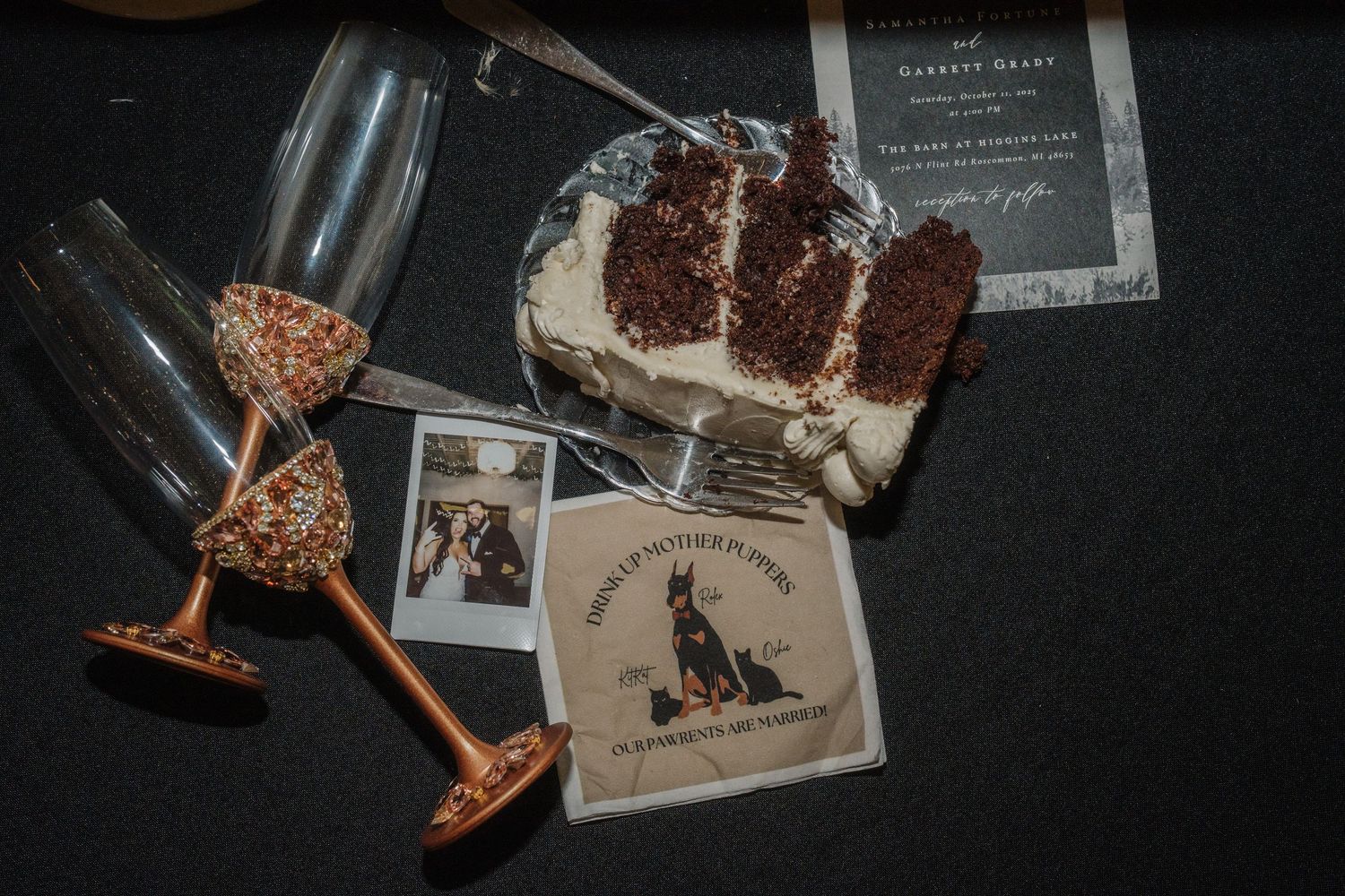 Wedding stationery and photographs arranged on a dark surface with elegant details and vintage styling.