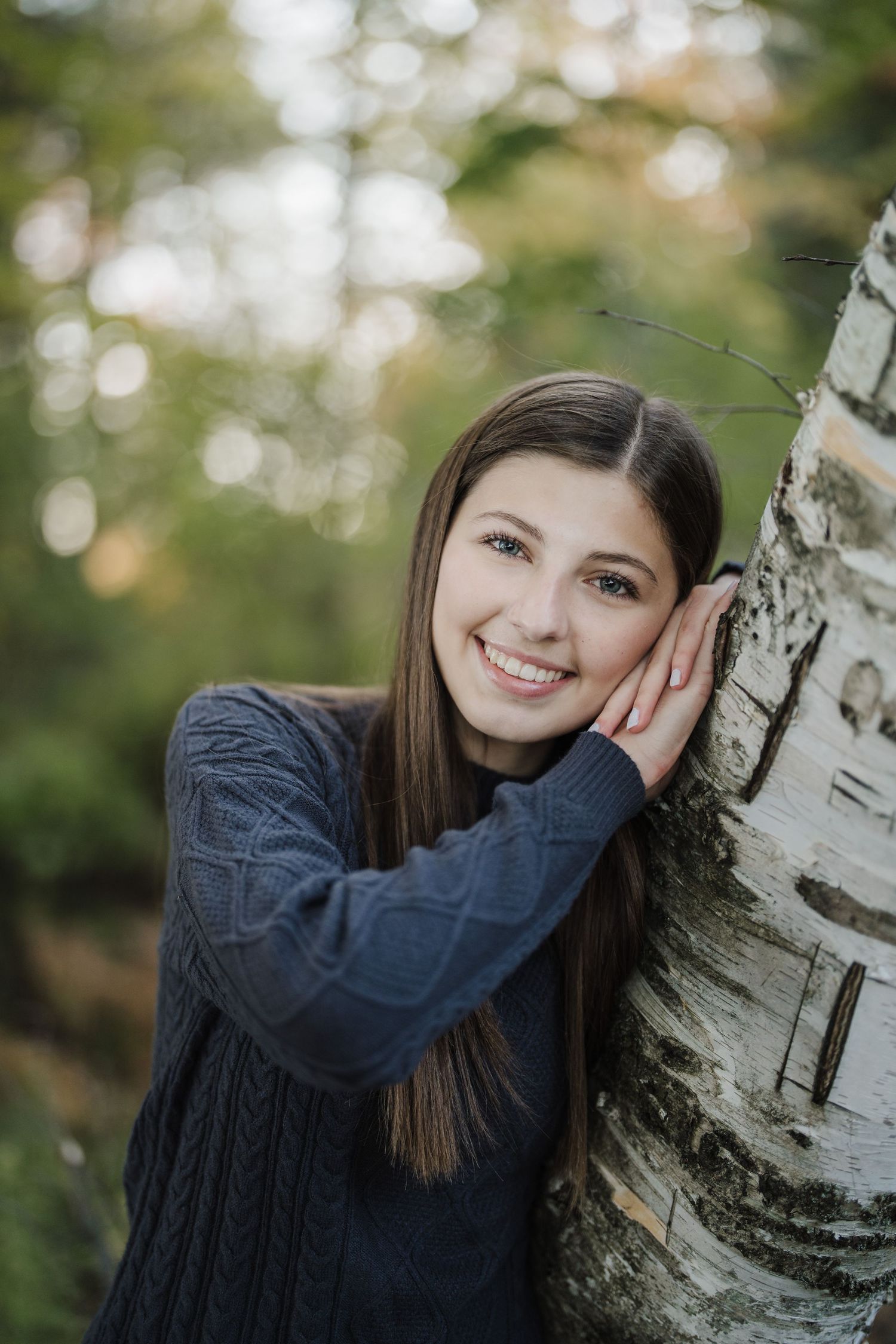 Portrait series against a birch tree trunk with soft bokeh background in a natural outdoor setting.
