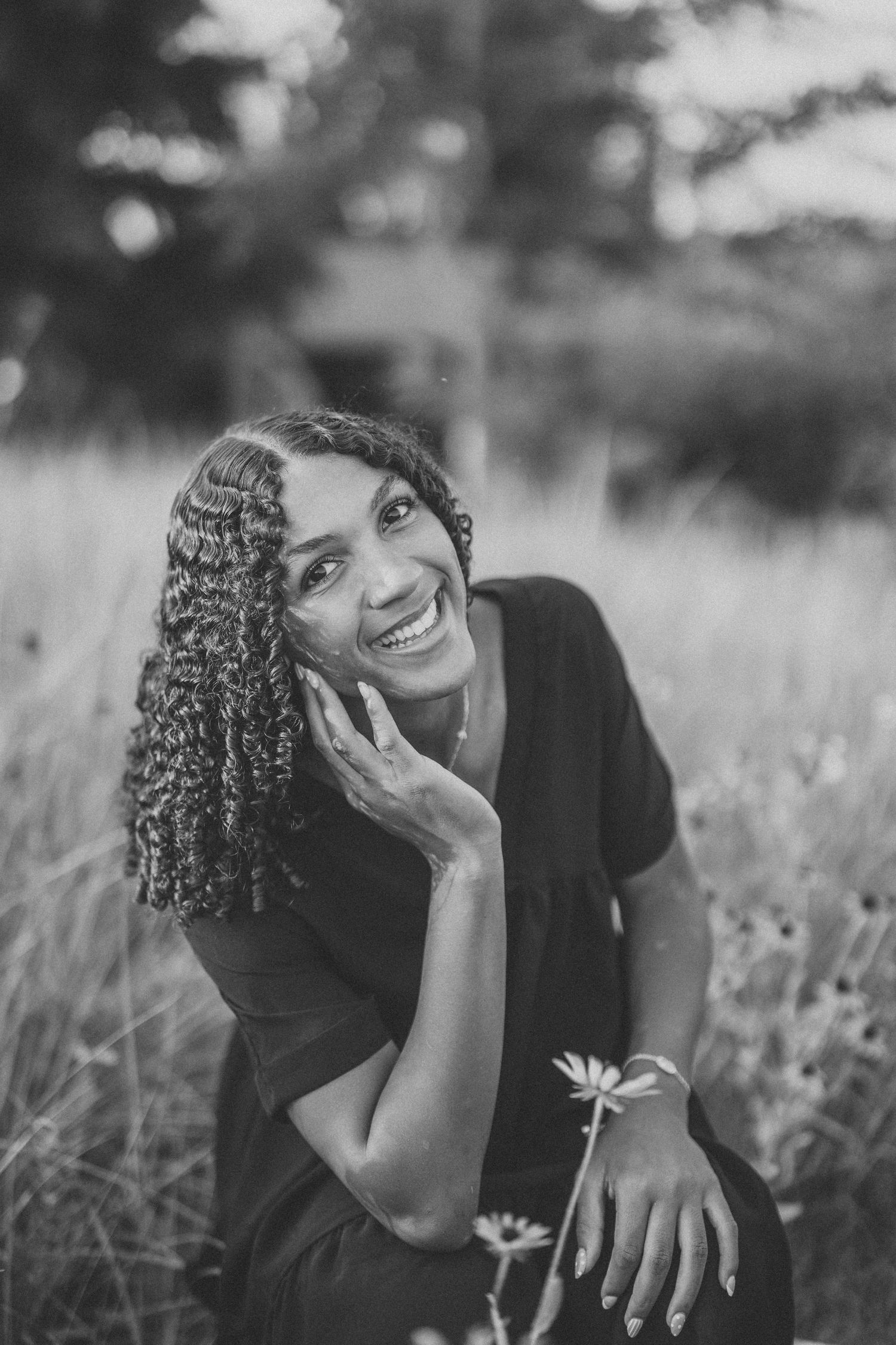 A candid black and white portrait showing joyful expressions while sitting in a wildflower field.