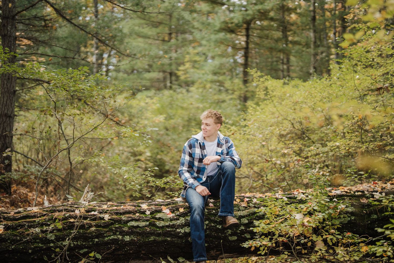 A family wearing denim and plaid poses together in a lush autumn forest setting.