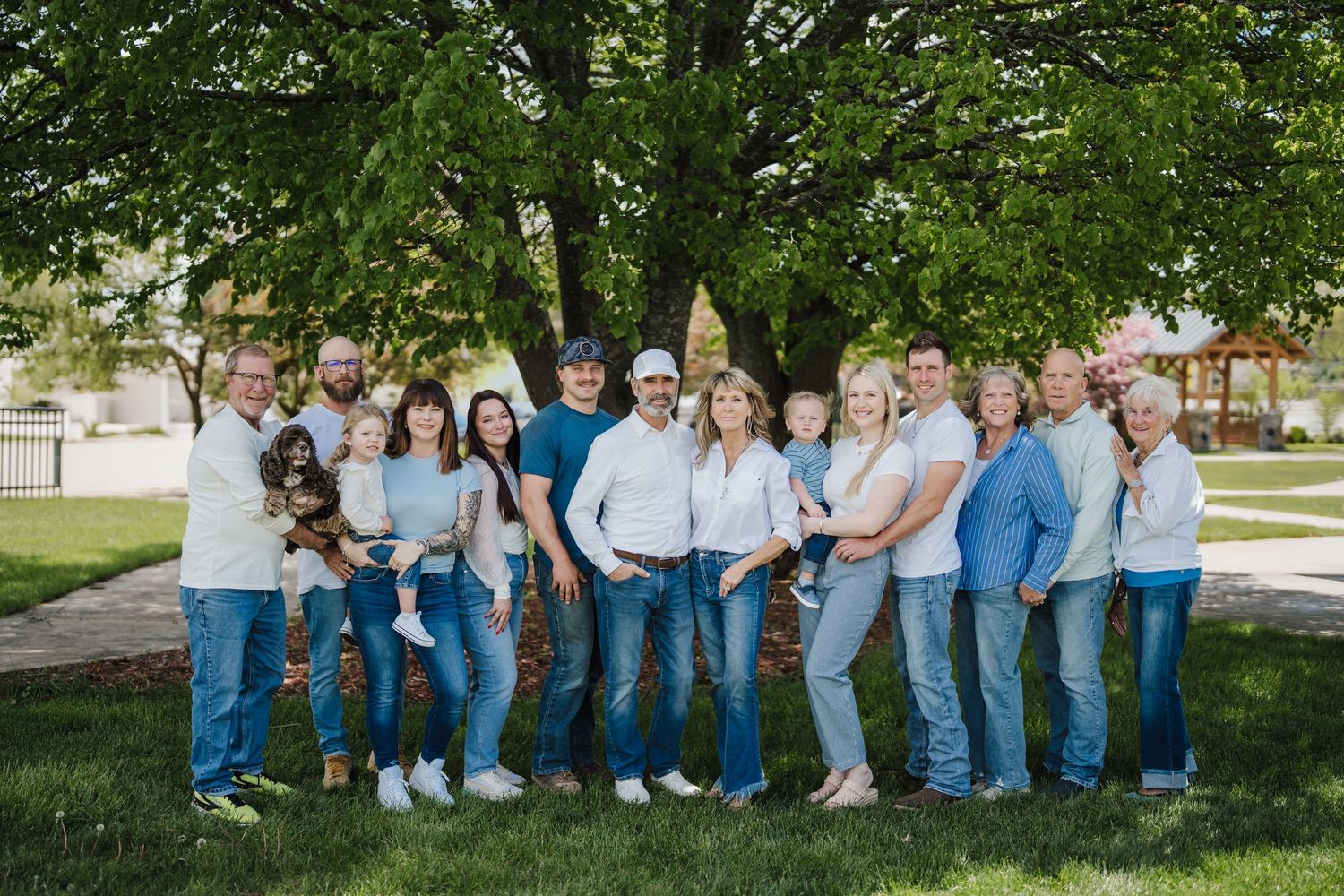 A group of people wearing coordinated blue jeans and white shirts sit together outdoors for a casual photo session.