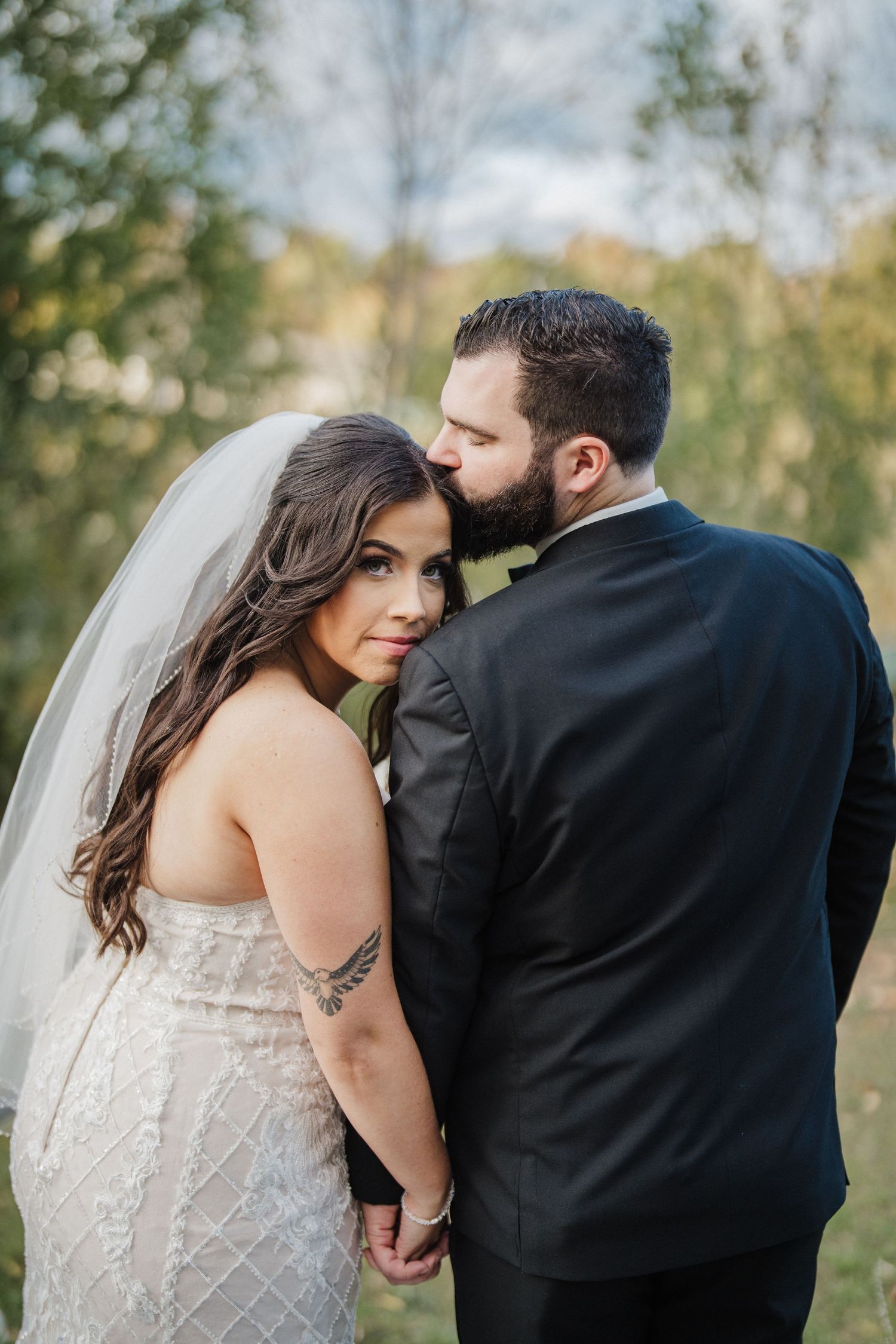 Intimate wedding portrait of couple against natural garden backdrop.