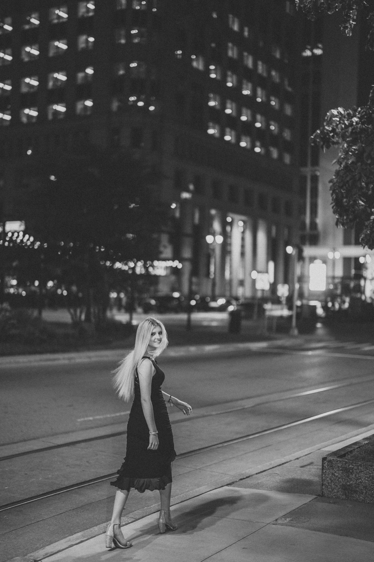 Black and white urban nightscape with string lights and city buildings creating moody ambiance.