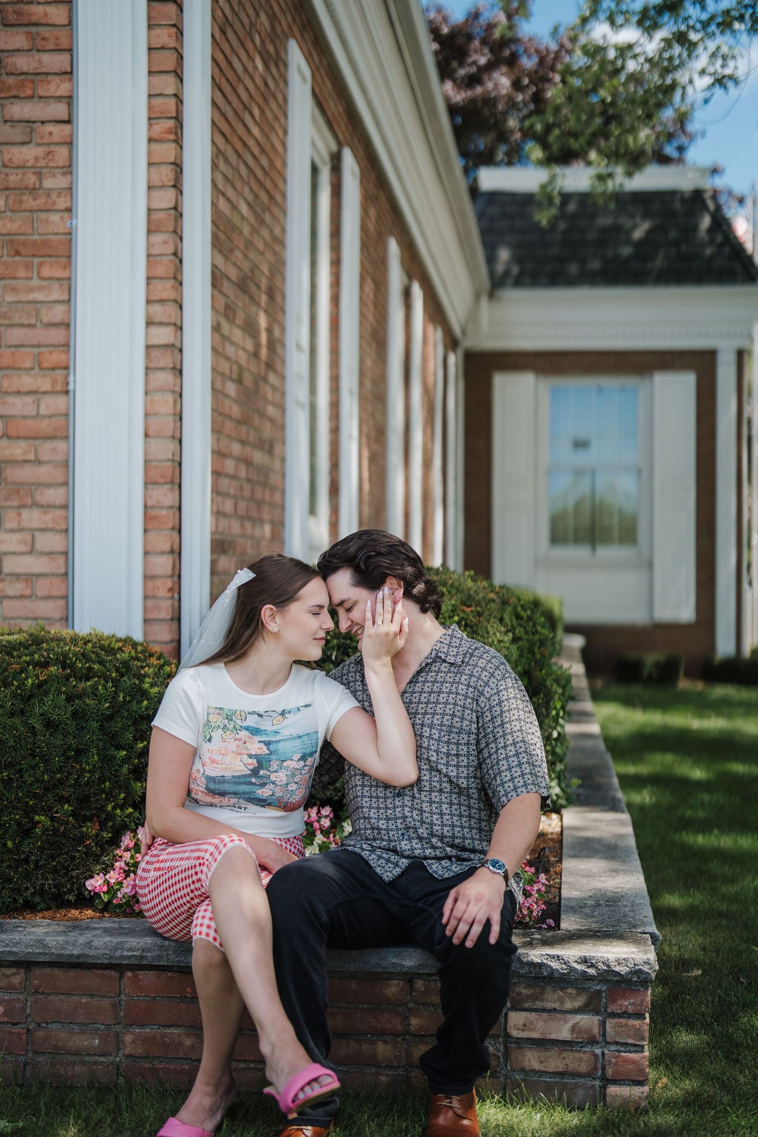 A couple sits together on brick steps outside a building with white columns on a sunny day.