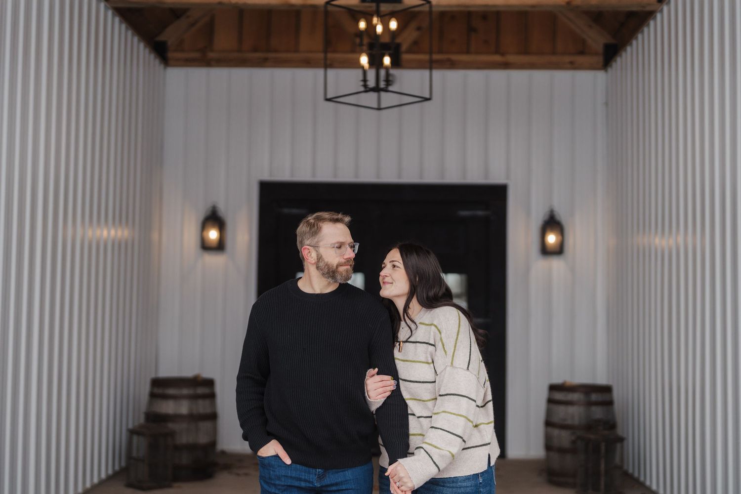 People gather in an elegant white-walled room with wooden beams and pendant lighting fixtures.