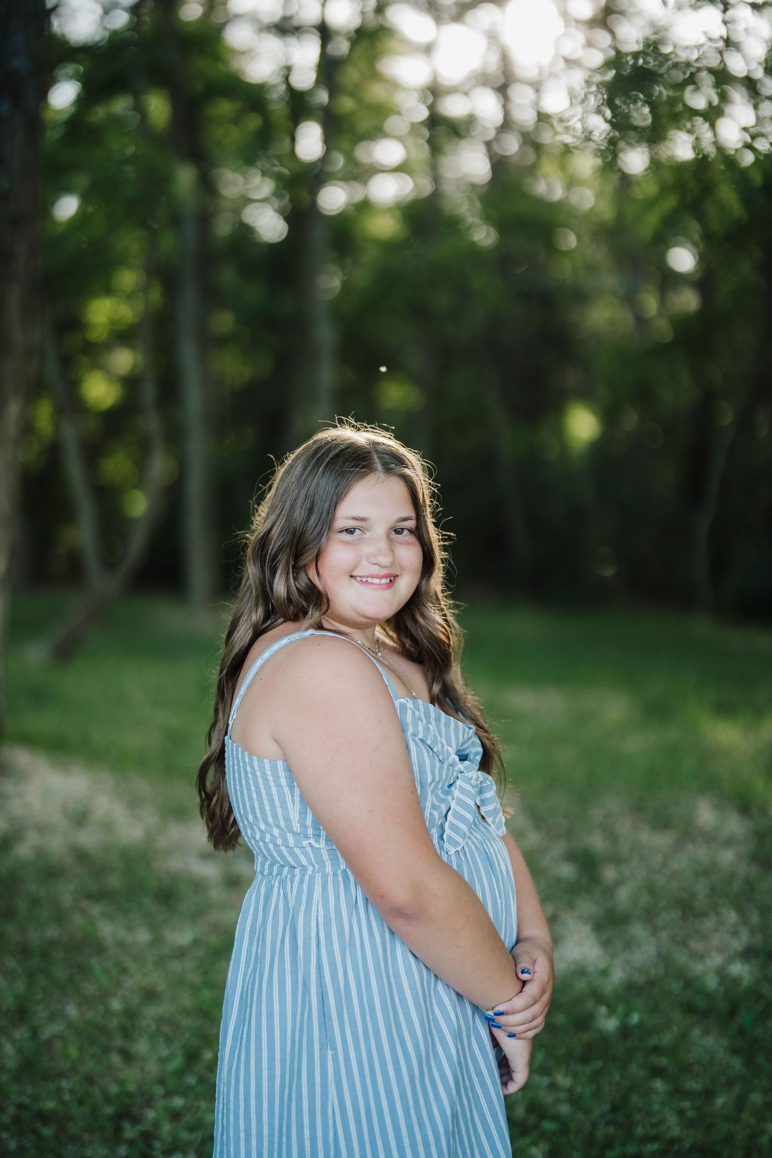 A series of outdoor portraits in a blue striped dress against a natural wooded background with wildflowers.