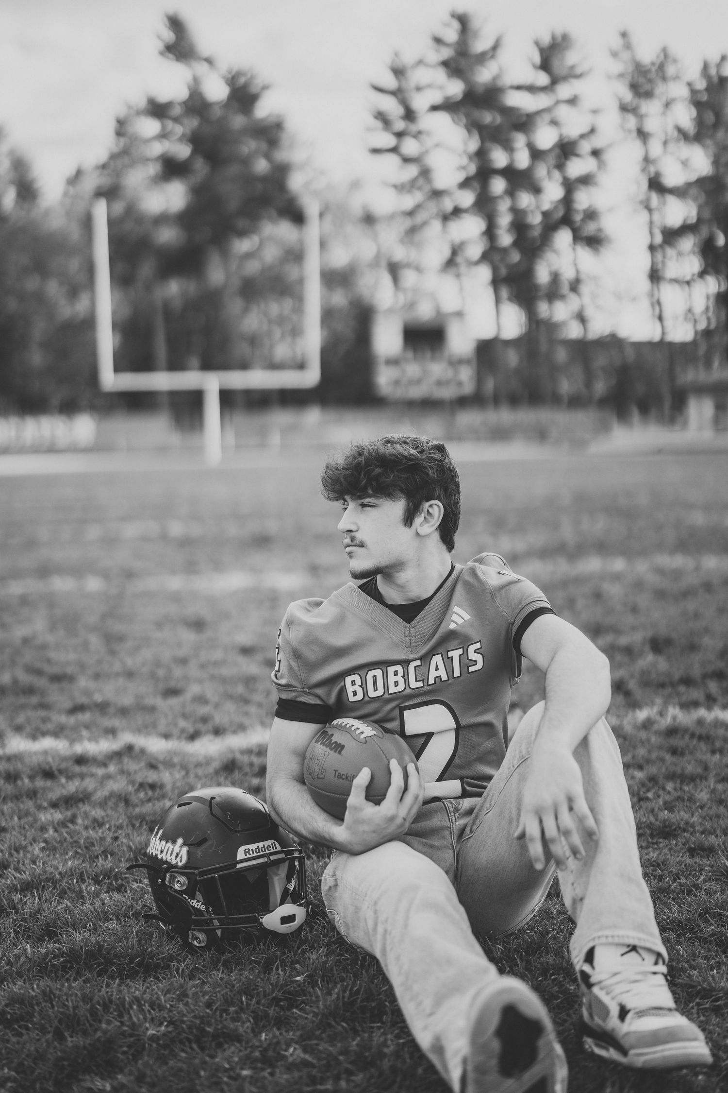 Black and white photo series of a person in a Bobcats jersey relaxing on a football field with goal posts visible.