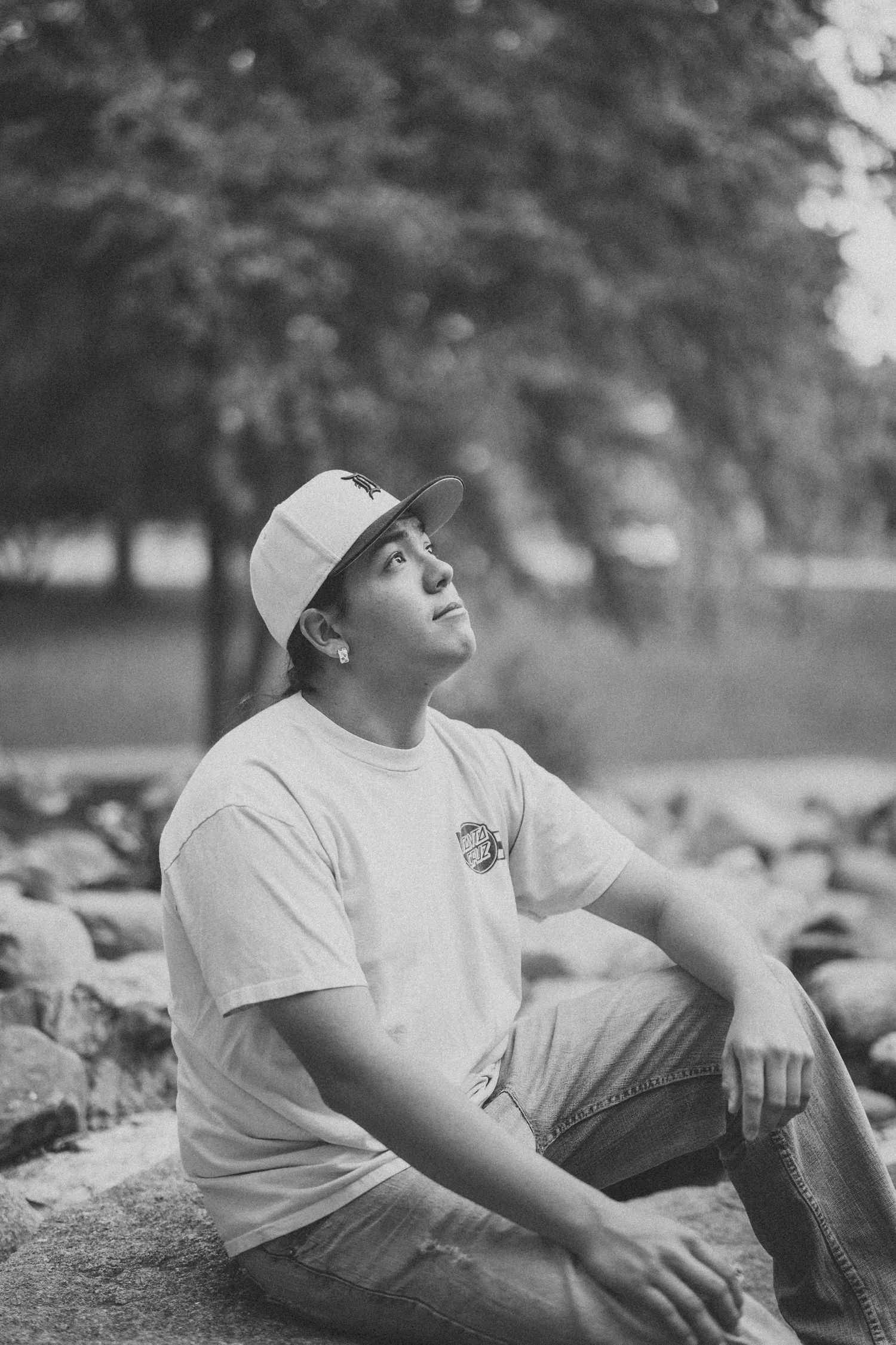 A black and white photo series showing someone in a white t-shirt and baseball cap lounging outdoors.