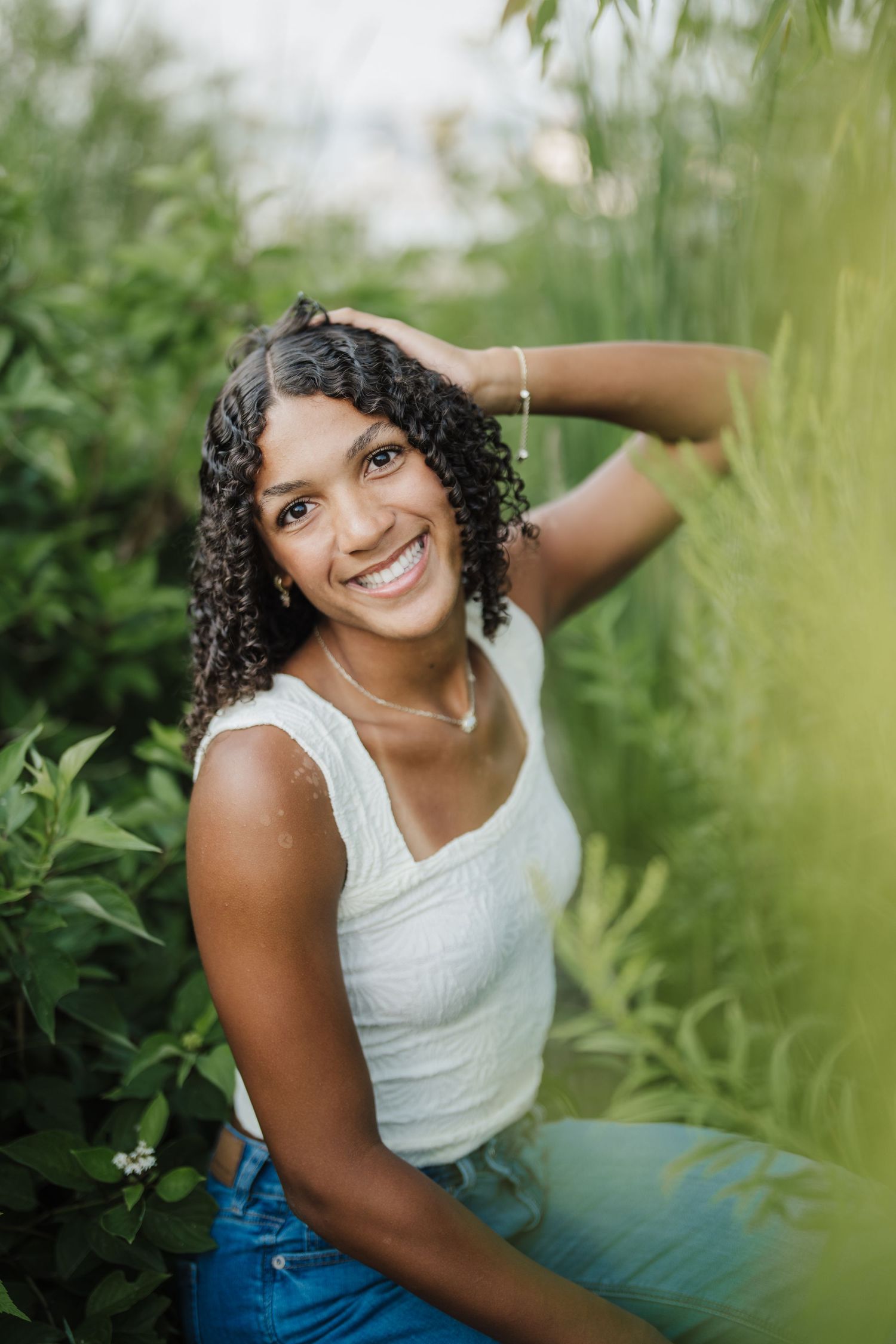 Natural outdoor portrait series featuring casual summer style with white top and denim in lush greenery.