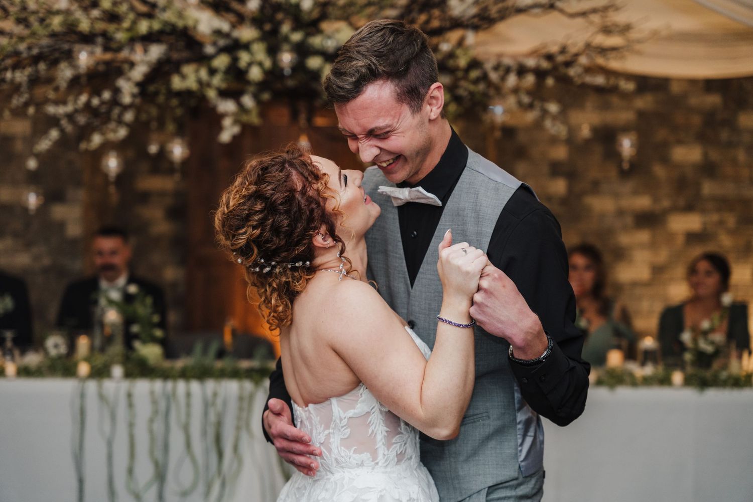 Reception dance moment captured with rustic stone wall and floral backdrop.