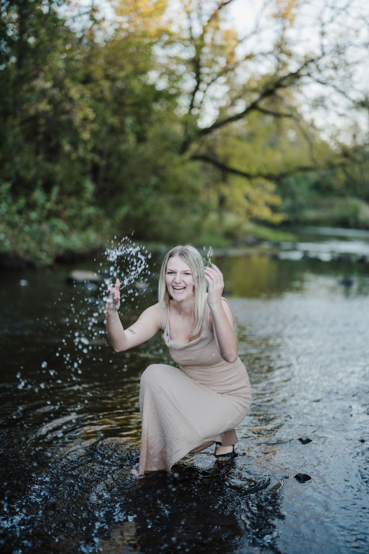 Playful splashing and movement captured by a pond with rocks and autumn foliage in the background.