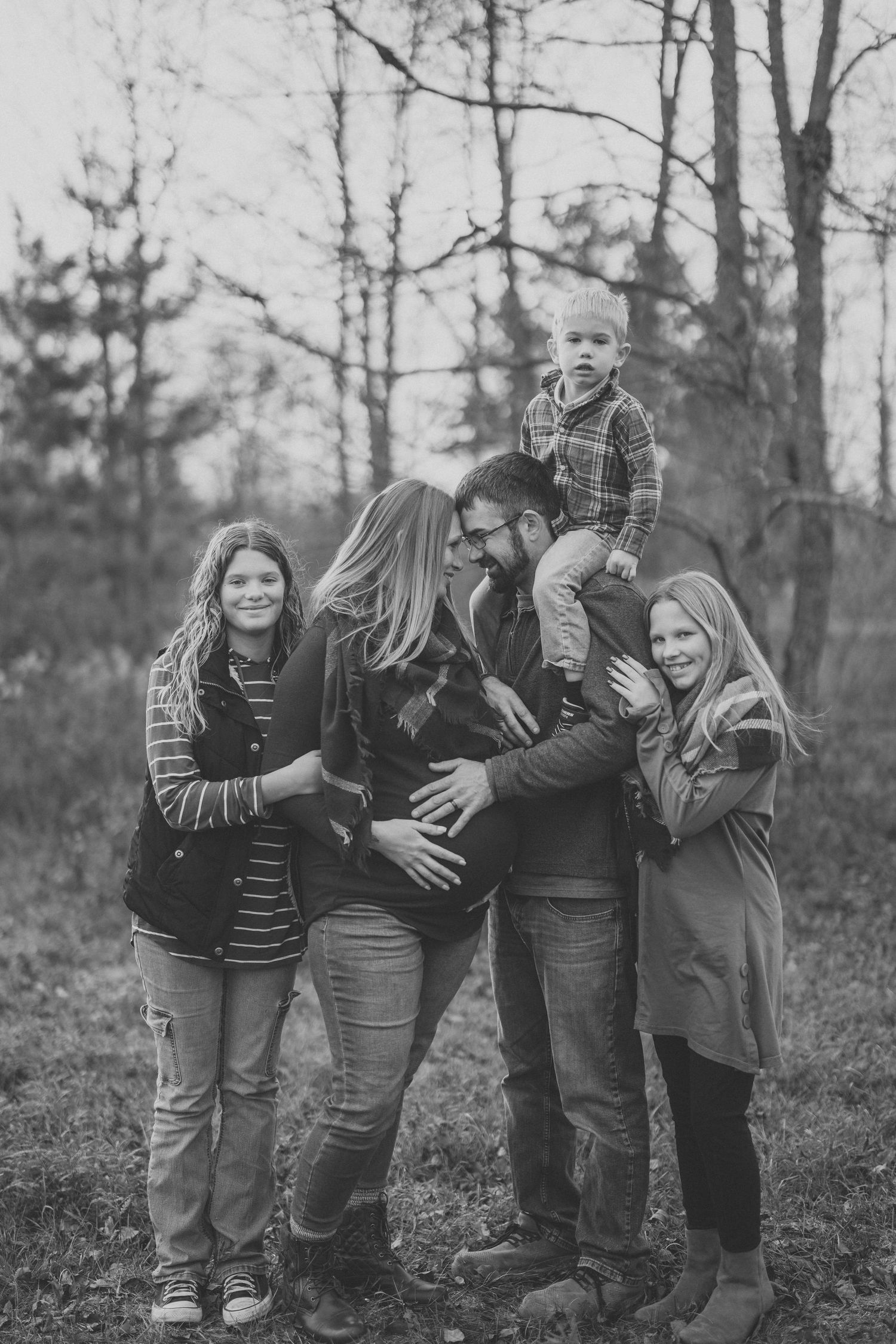 A series of black and white photos showing a group of people posing playfully together outdoors among trees.