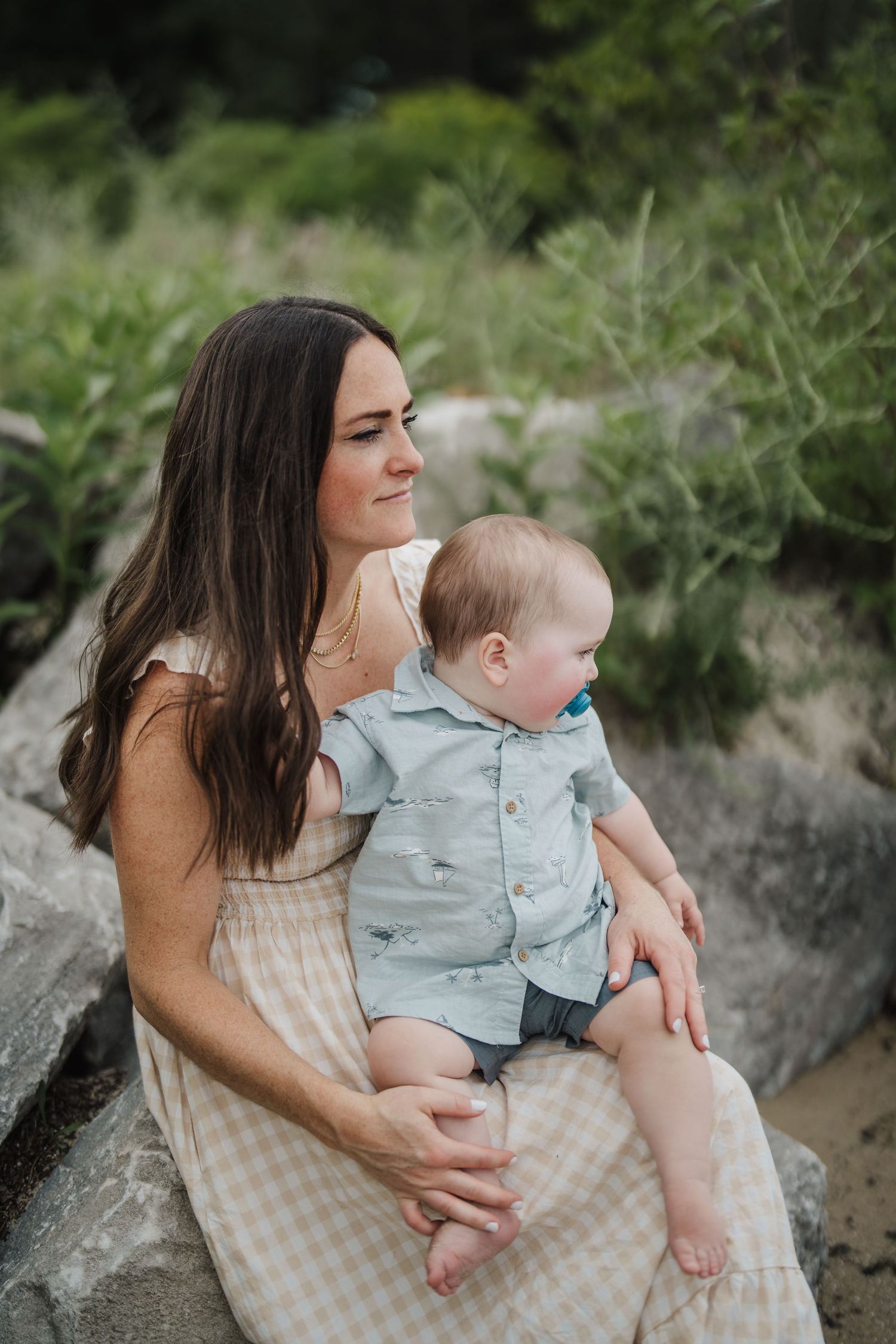 A tender moment between parent and baby sitting on rocky terrain.