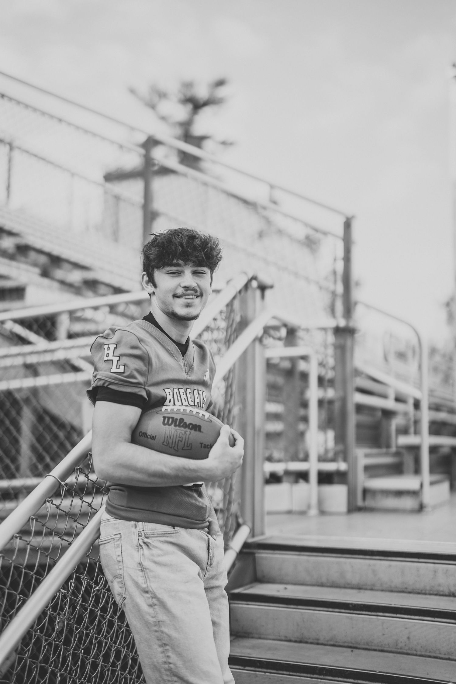 Black and white photo series of a young athlete sitting on bleachers in a sports uniform.