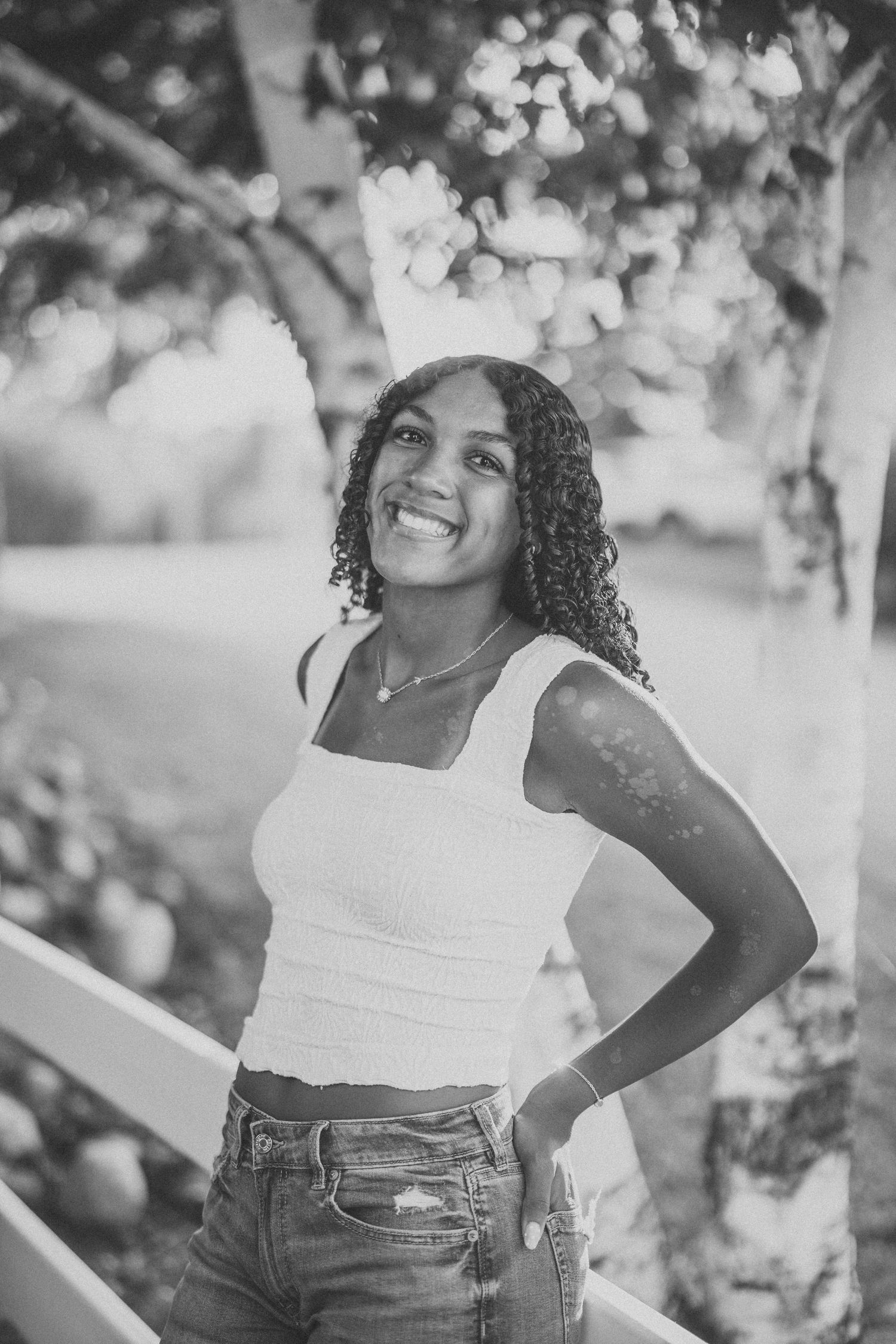 Black and white portrait series showing joyful expressions against a natural outdoor background.