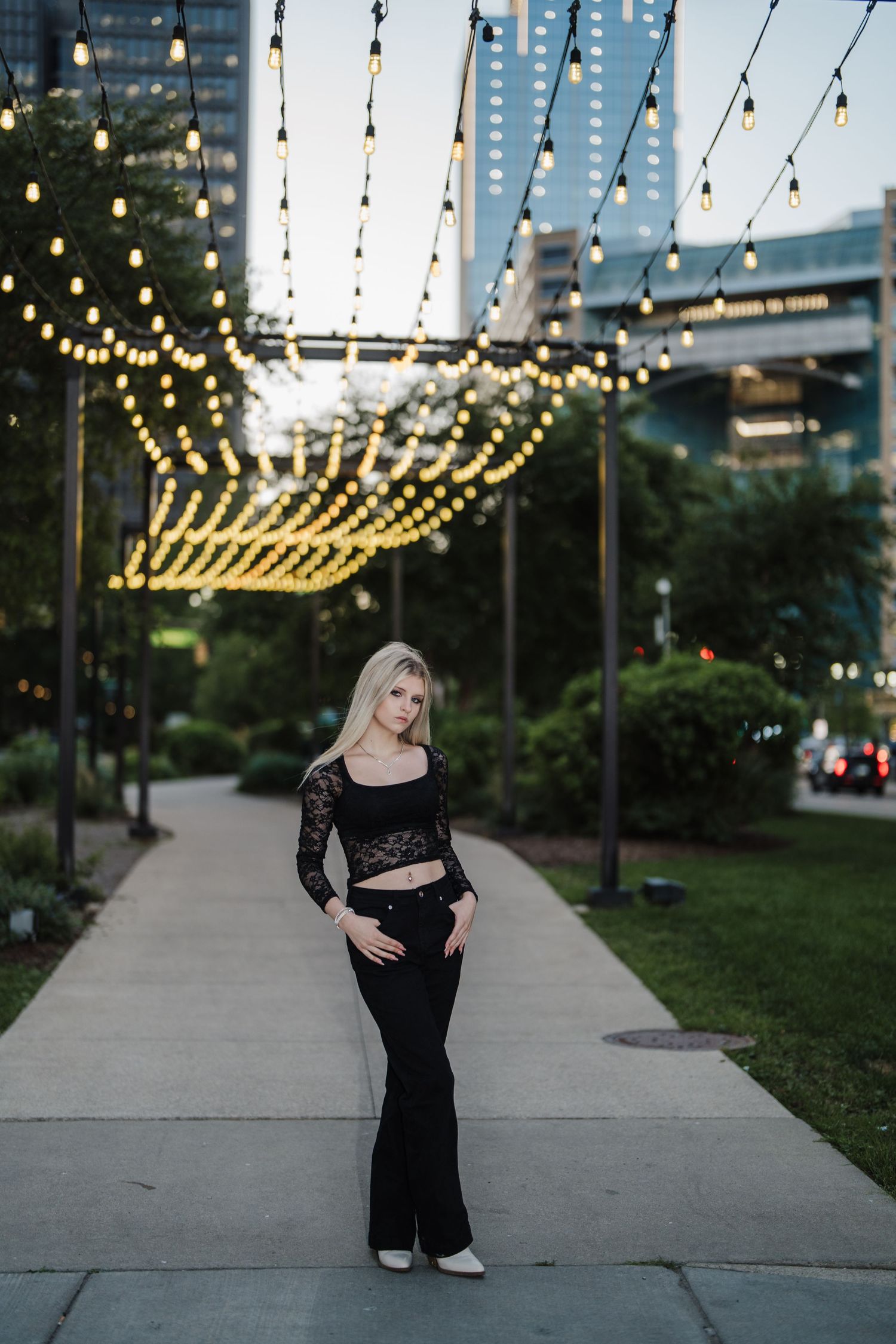 A series of outdoor evening photos under string lights showing a black dress against an urban backdrop.