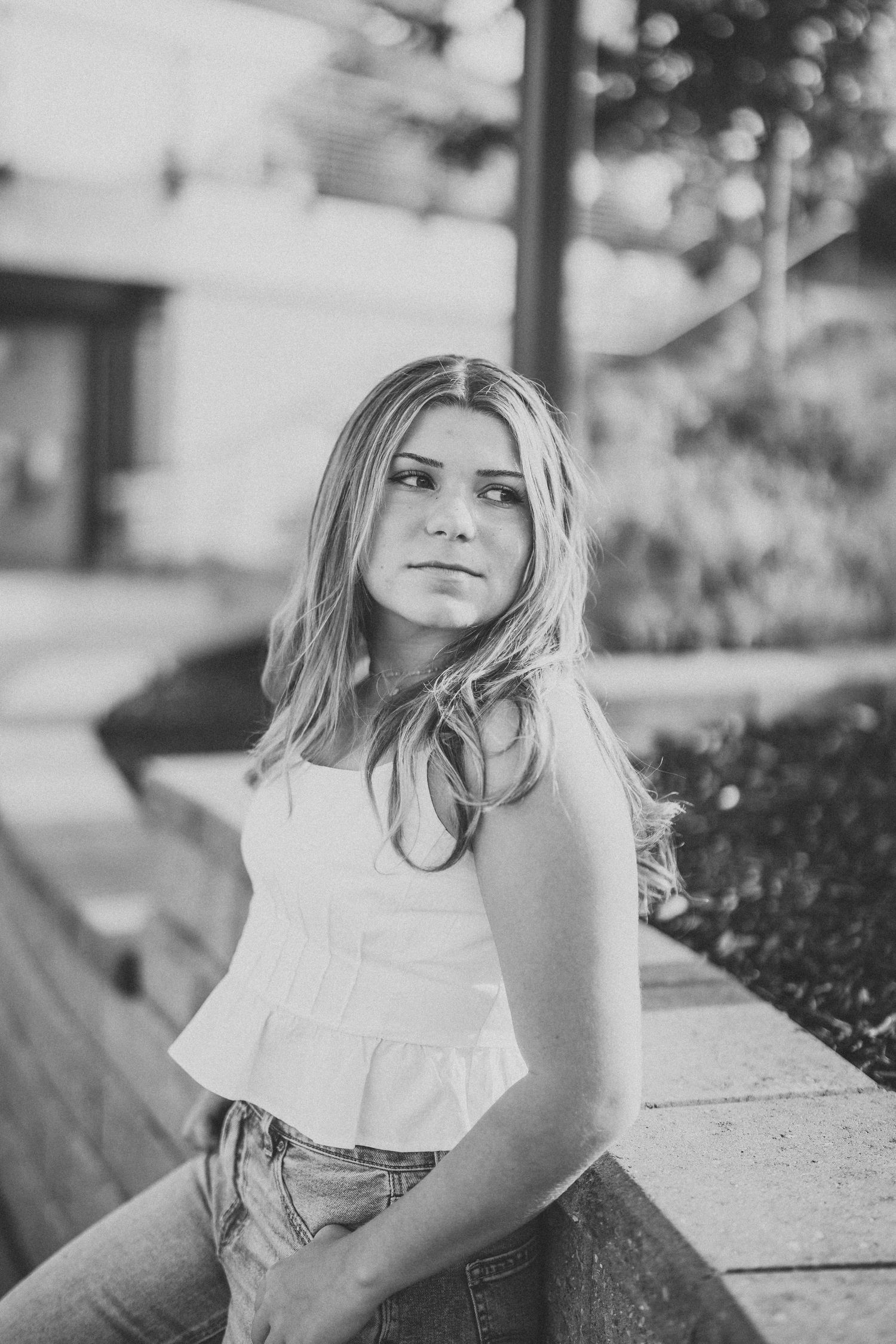 Black and white portrait series showing a person in a white ruffled top sitting outdoors in natural lighting.