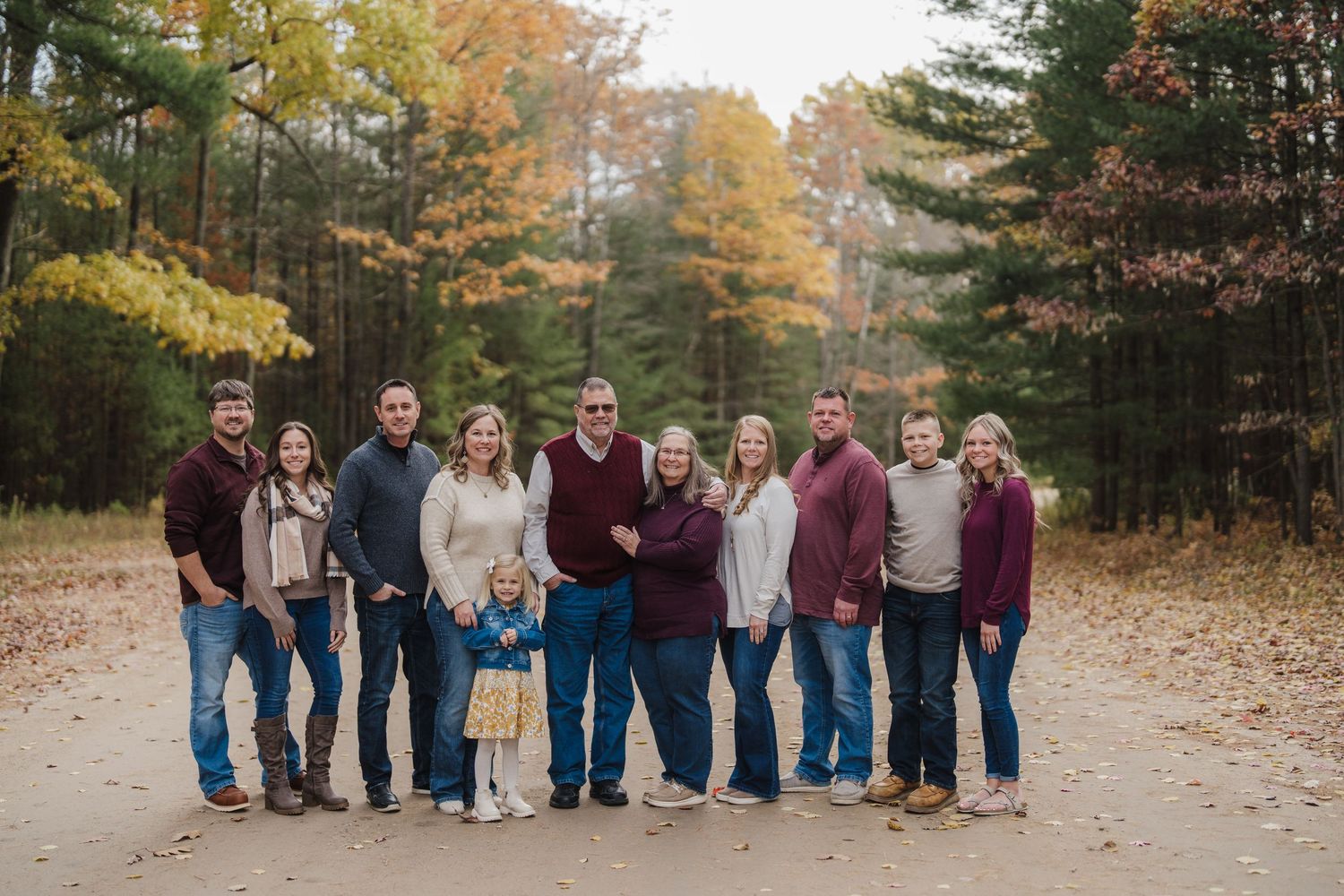 A series of outdoor family group photos taken in a scenic autumn setting with colorful fall foliage in the background.