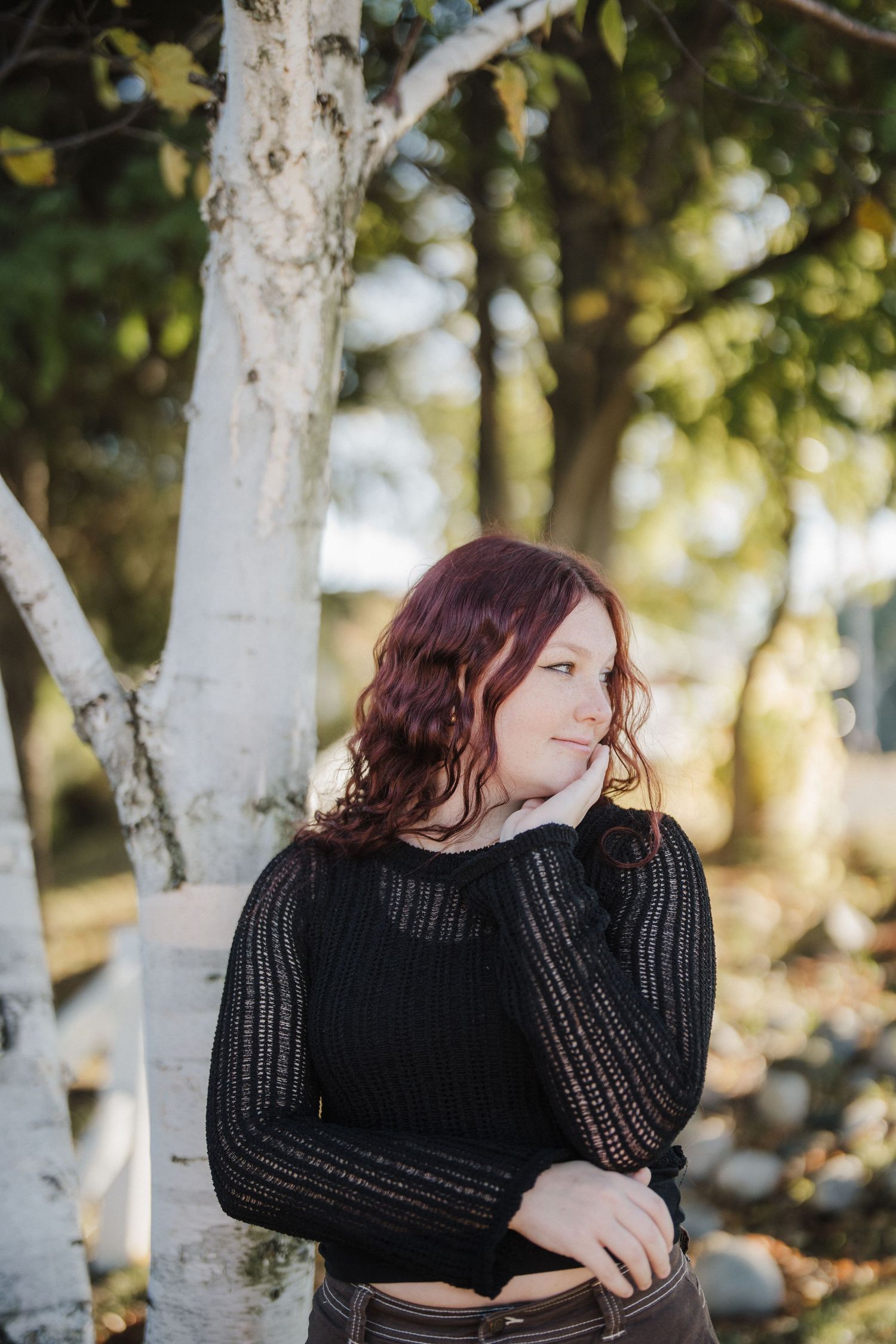 Natural light portrait against white birch tree trunk with soft bokeh background.