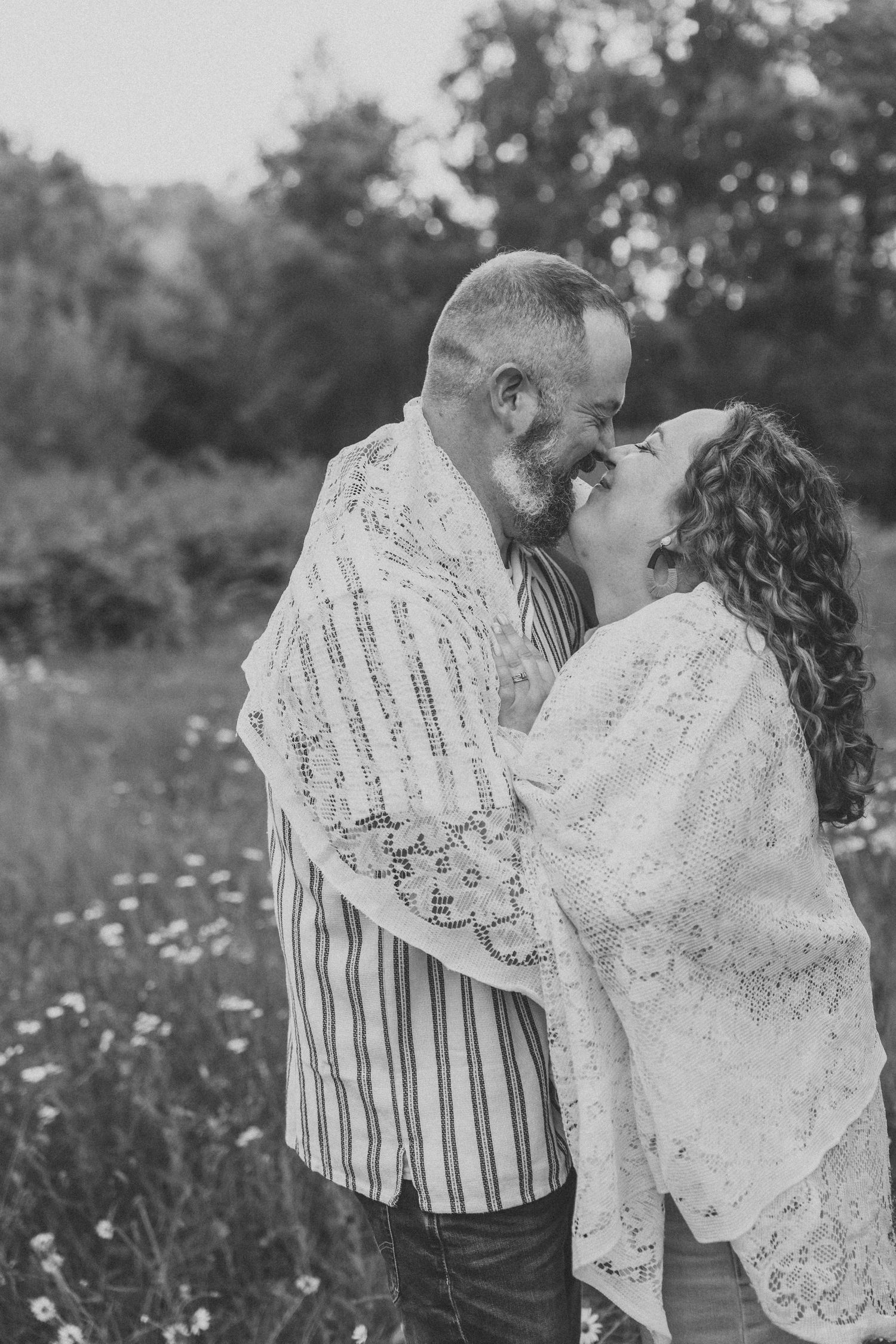 Black and white photo of a loving couple about to kiss in a wildflower field.