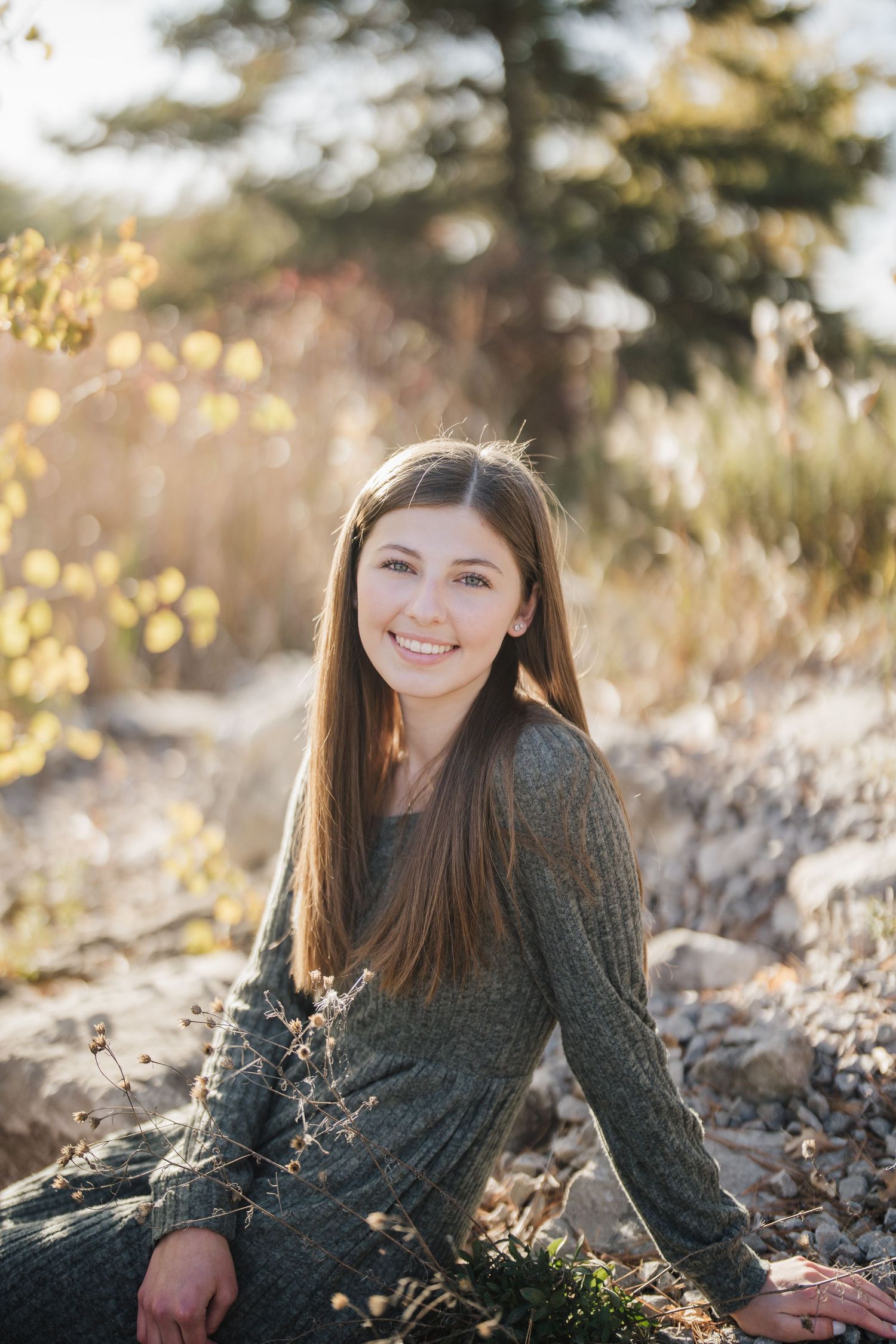 A series of outdoor portrait photos showing someone in a dark sweater lying in sunlit autumn grass and foliage.